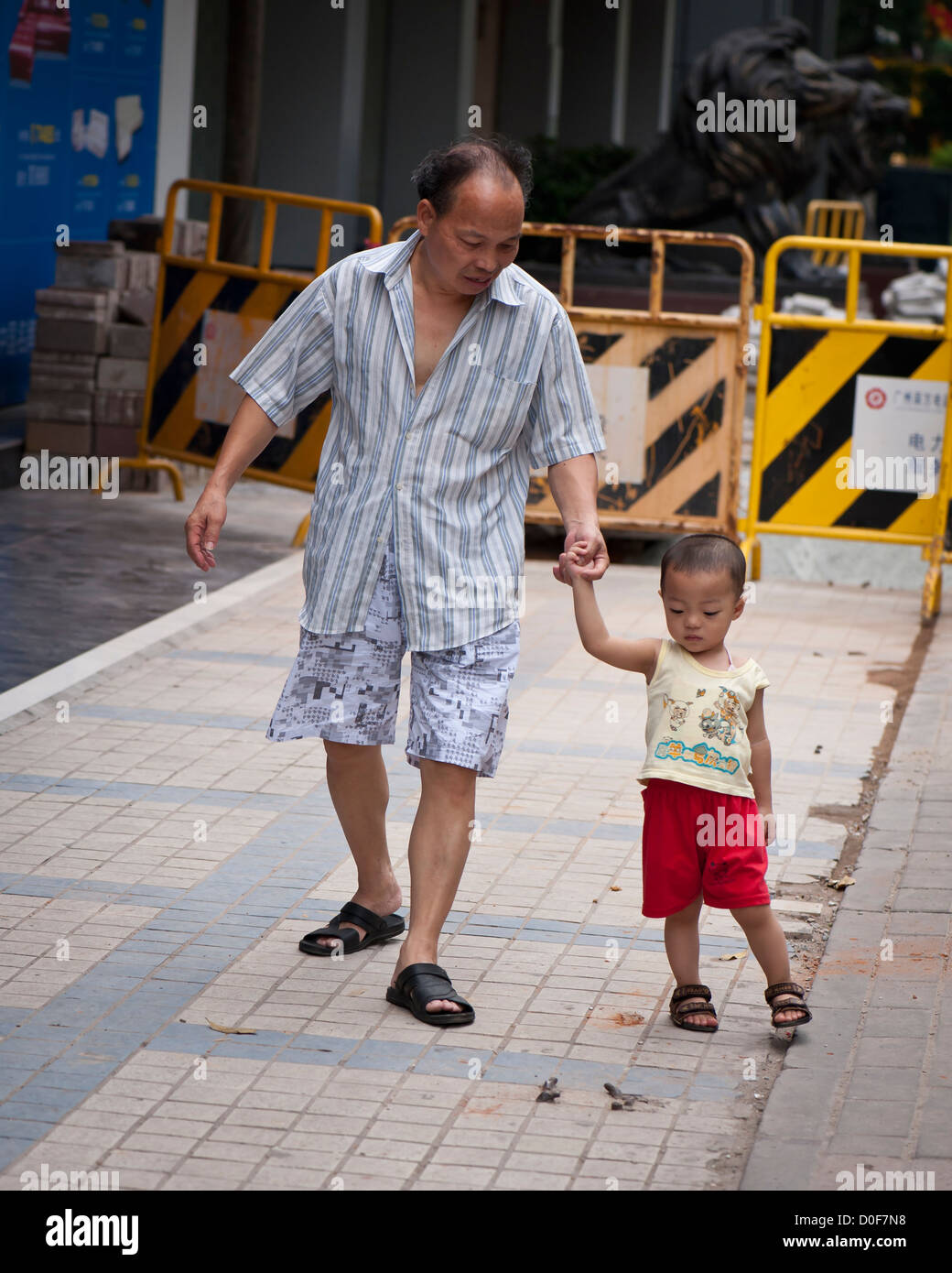 Nonno avverte il nipote di guardare fuori per il dog poo, Guangzhou Foto Stock