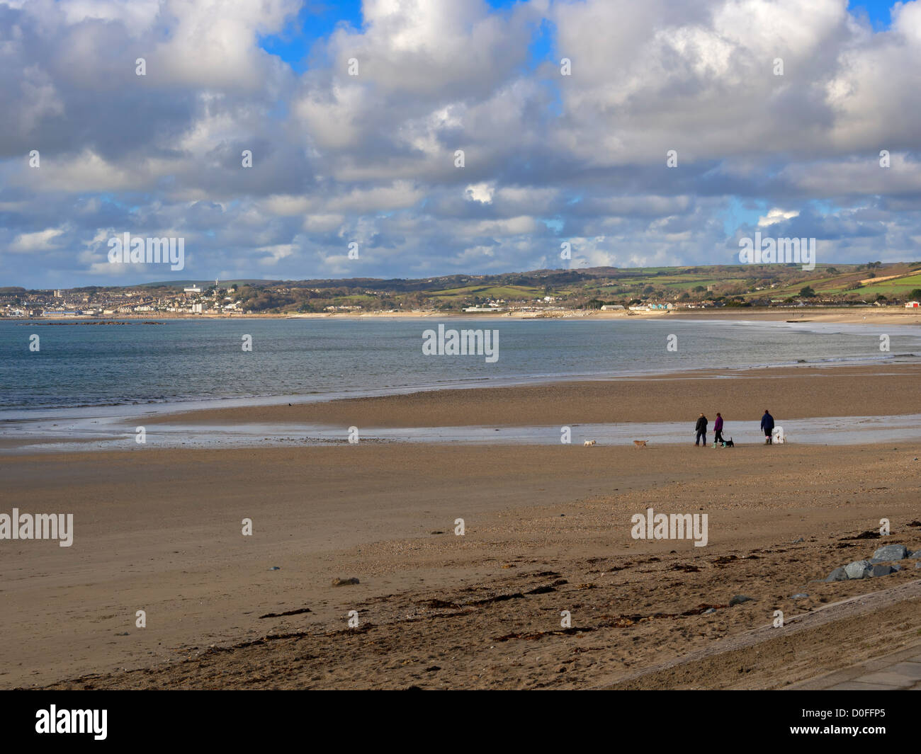 Mounts Bay beach e a Penzance da Marazion, Cornwall. Tre persone che camminano i loro cani sulla spiaggia in autunno. Foto Stock
