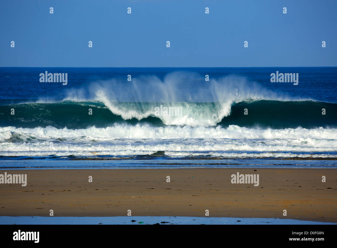 Portreath, Cornwall. Un'onda si rompe sulla spiaggia. Foto Stock