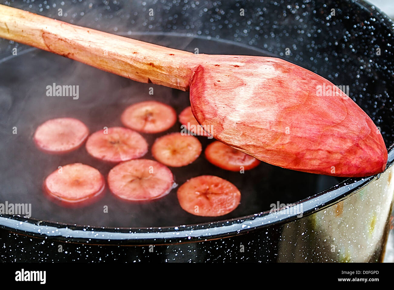 Vino rosso con pezzi di apple, bollire in una grande ciotola e mescolare con un cucchiaio di legno. Tradizione rumena per il tempo freddo dell'anno. Foto Stock