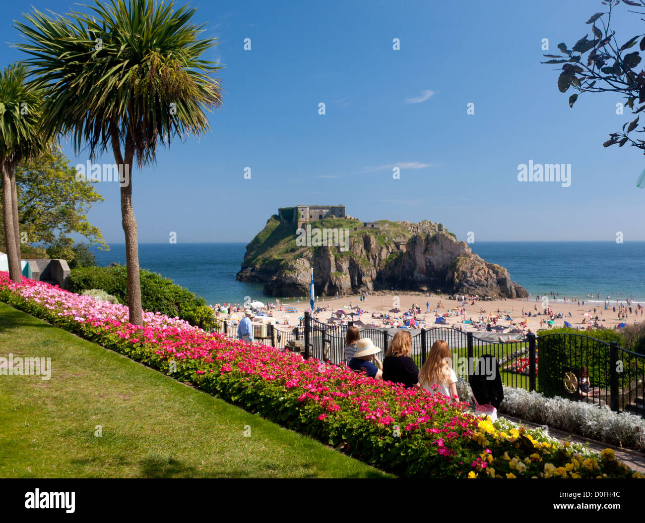 La gente seduta in un giardino affacciato sulla spiaggia del Castello e di Santa Caterina di Isola Tenby Pembrokeshire West Wales UK Foto Stock