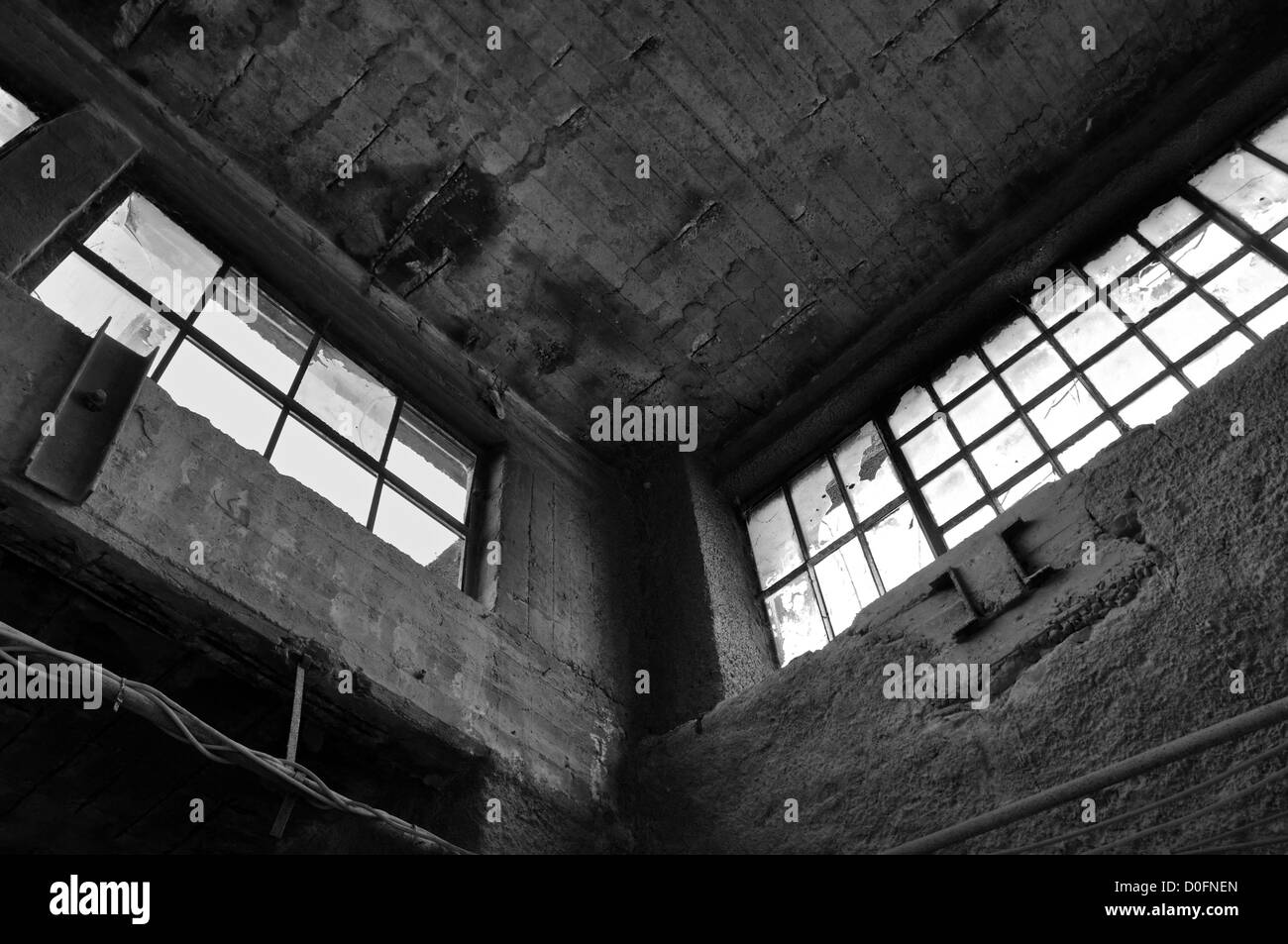 Finestre rotte muro di cemento e soffitto in fabbrica abbandonati. In bianco e nero. Foto Stock