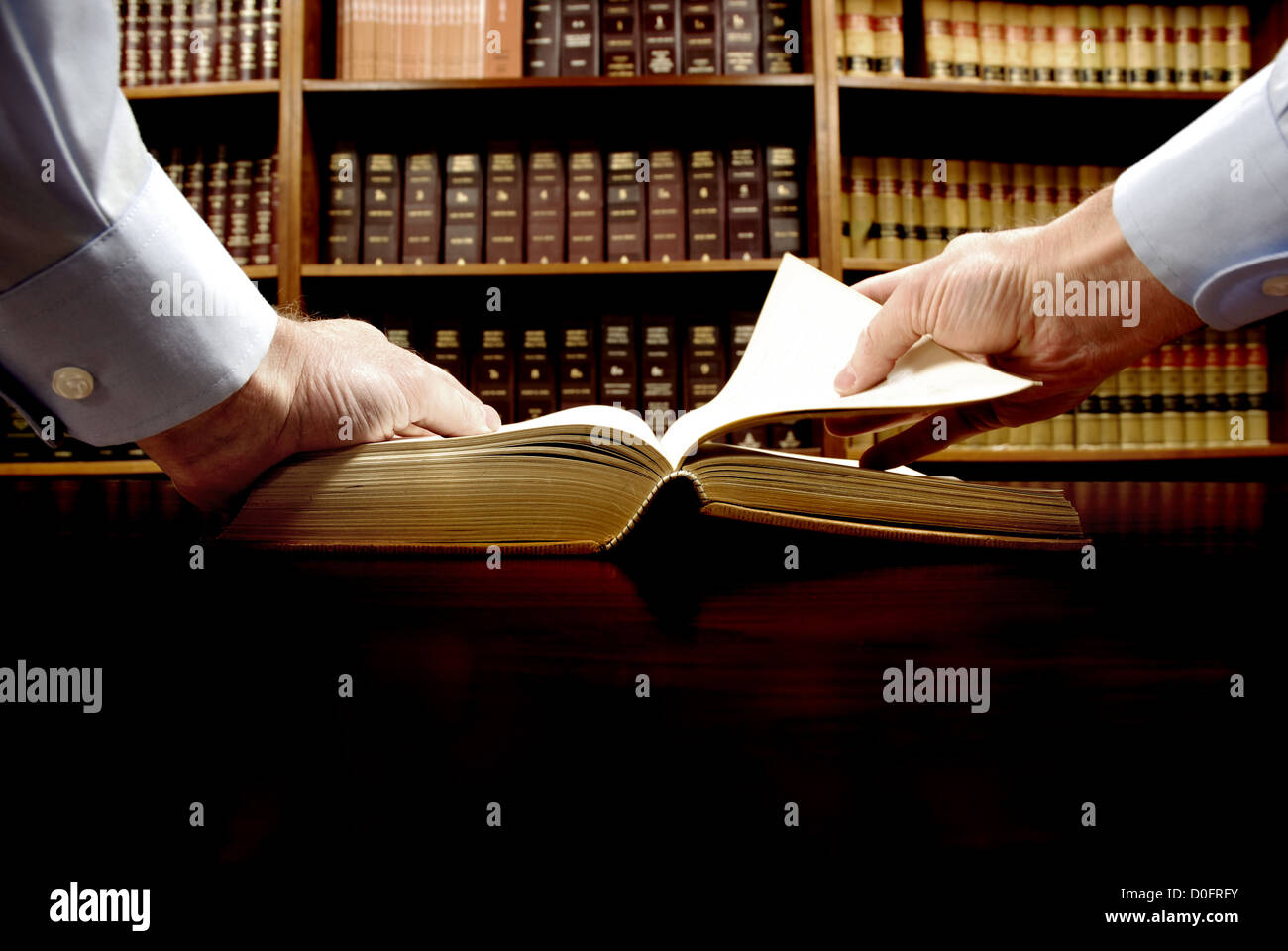 Le mani sono in possesso di un vecchio libro con Libreria in background Foto Stock