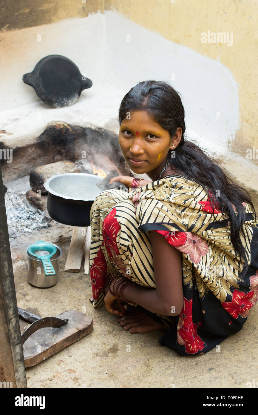 Sud giovane donna indiana di latte bollente su un fuoco aperto nel suo villaggio rurale home. Andhra Pradesh, India Foto Stock