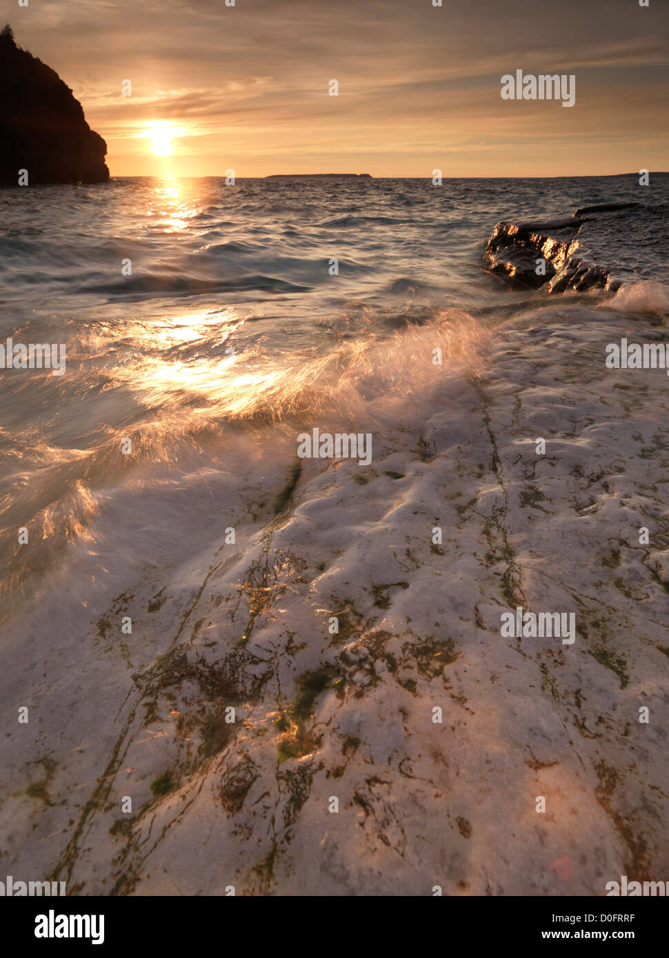 Acqua urtare contro le rocce di Georgian Bay. Tramonto paesaggio paesaggio naturale in colori dorati. Bruce penisola parco nazionale Foto Stock