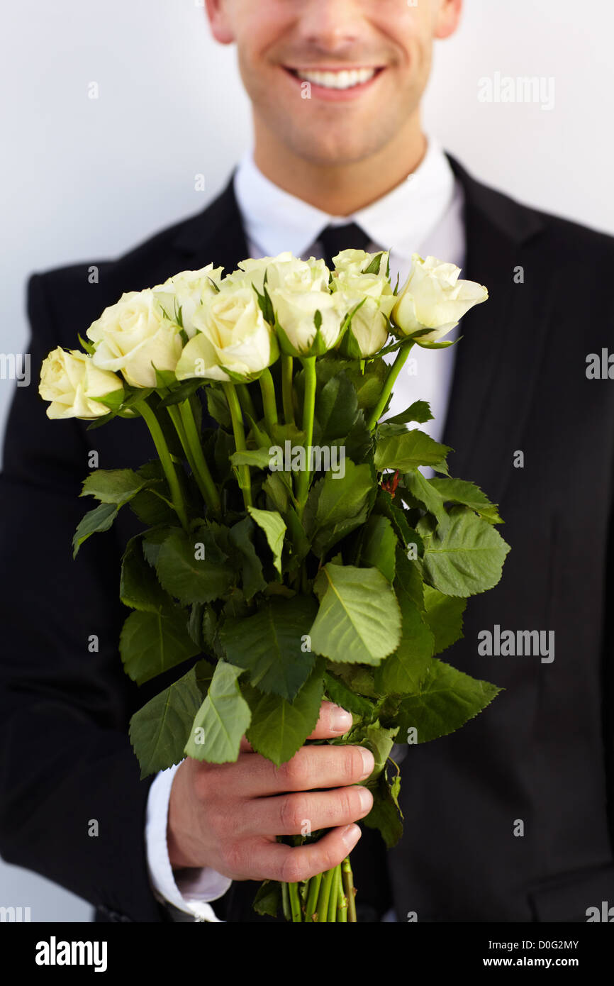 Giovane gentiluomo presenta un bouquet di rose come un dono Foto Stock