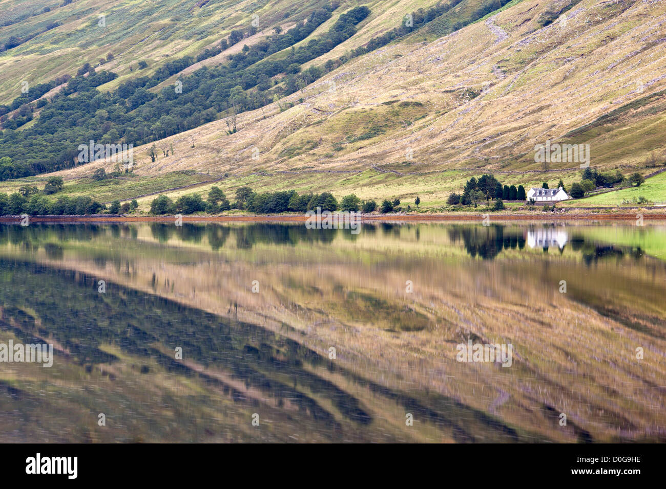 Colline circostanti e la casa si riflette nella superficie calma del Loch Fyne vicino a St Catherines, Argyll, Scotland, Regno Unito Foto Stock