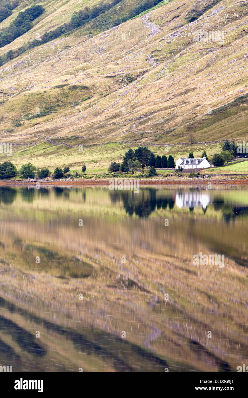 Colline circostanti e la casa si riflette nella superficie calma del Loch Fyne vicino a St Catherines, Argyll, Scotland, Regno Unito Foto Stock