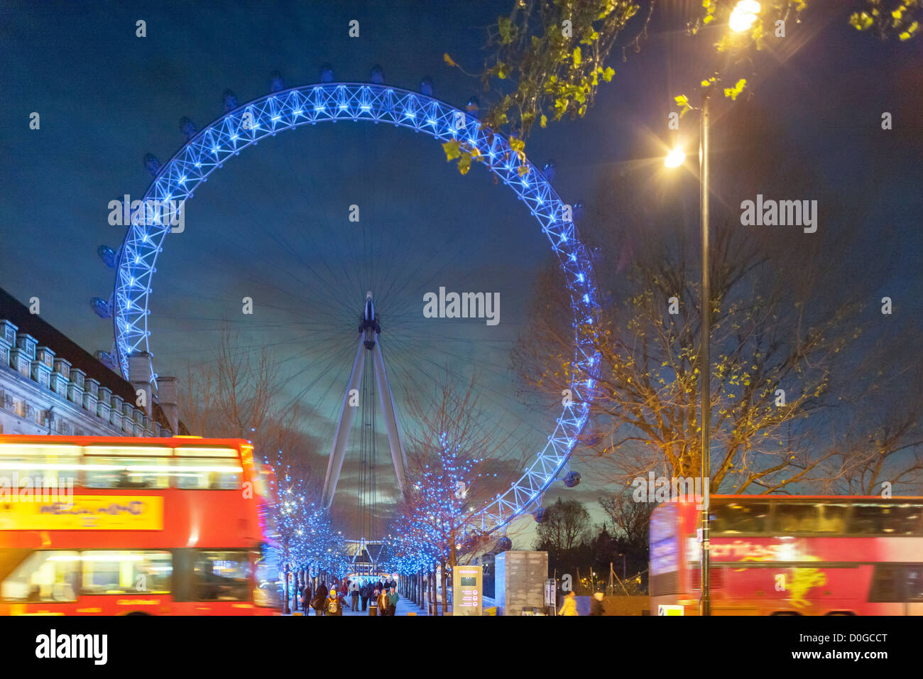 Il London Eye Millennium Wheel con blue di Natale le luci di Natale e double-decker bus al tramonto in inverno, Dicembre Foto Stock