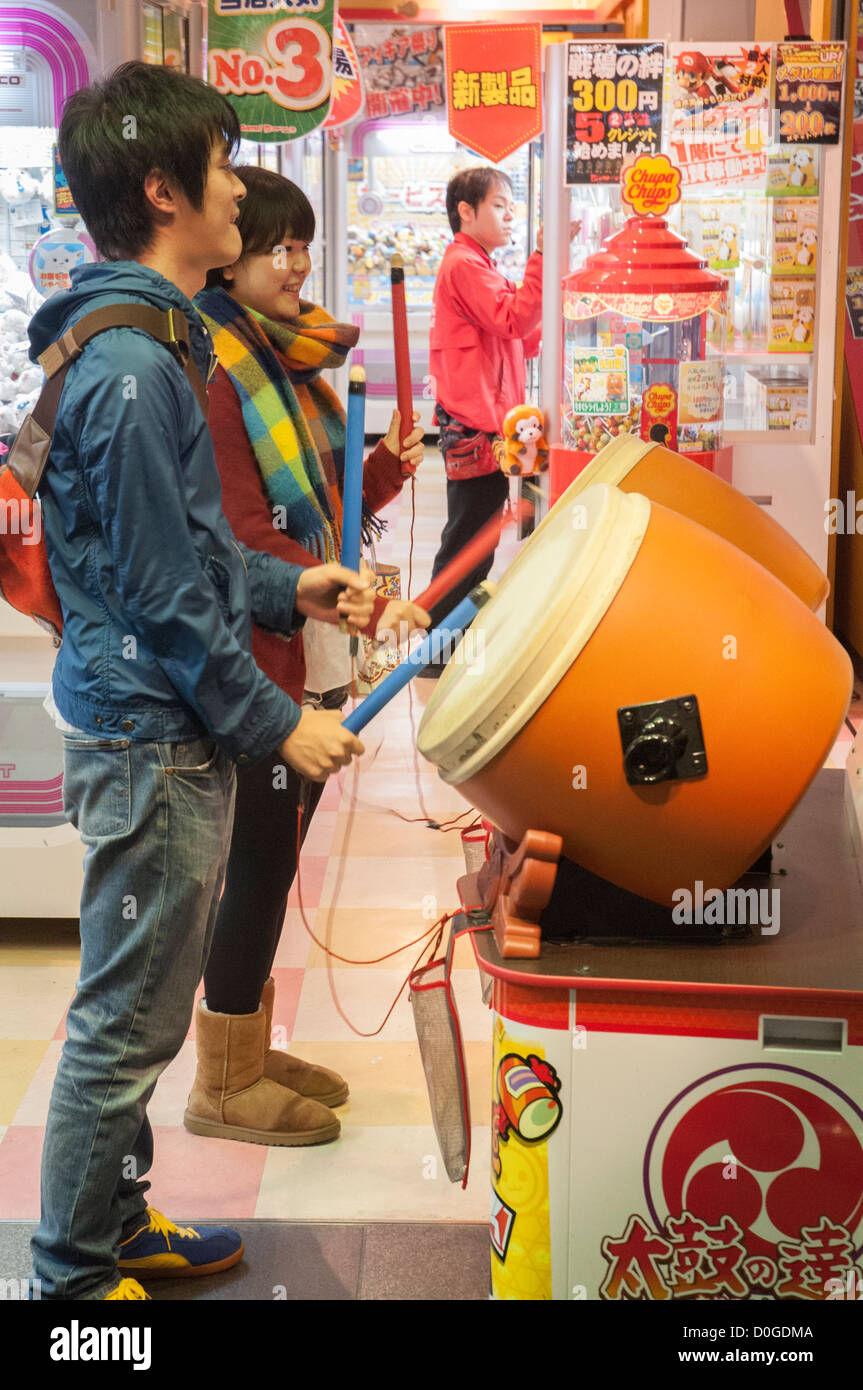 Giovani giapponesi maschi di tamburi in un salone di divertimenti in Ikebukuro, Tokyo Foto Stock