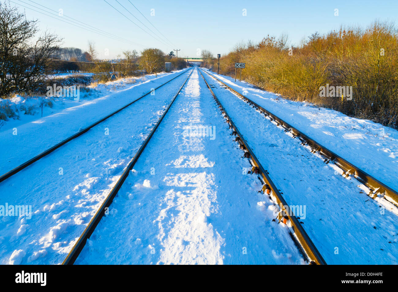 I binari ferroviari in esecuzione in una linea diritta attraverso la campagna dopo la neve invernale, Nottinghamshire, England, Regno Unito Foto Stock