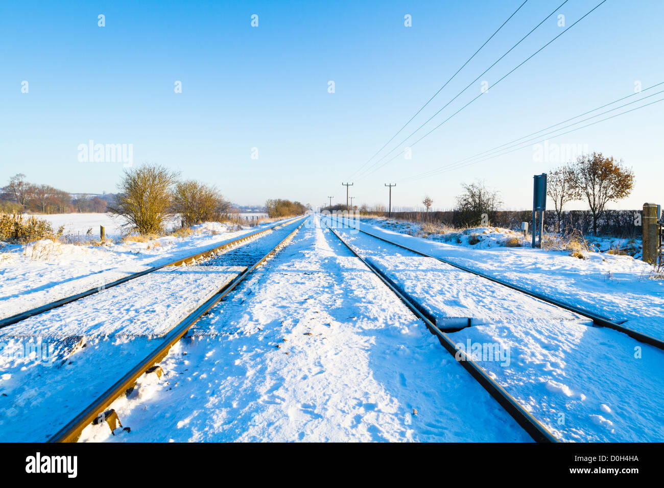 In inverno la neve su binari ferroviari in esecuzione in una linea retta attraverso il Nottinghamshire campagna, England, Regno Unito Foto Stock