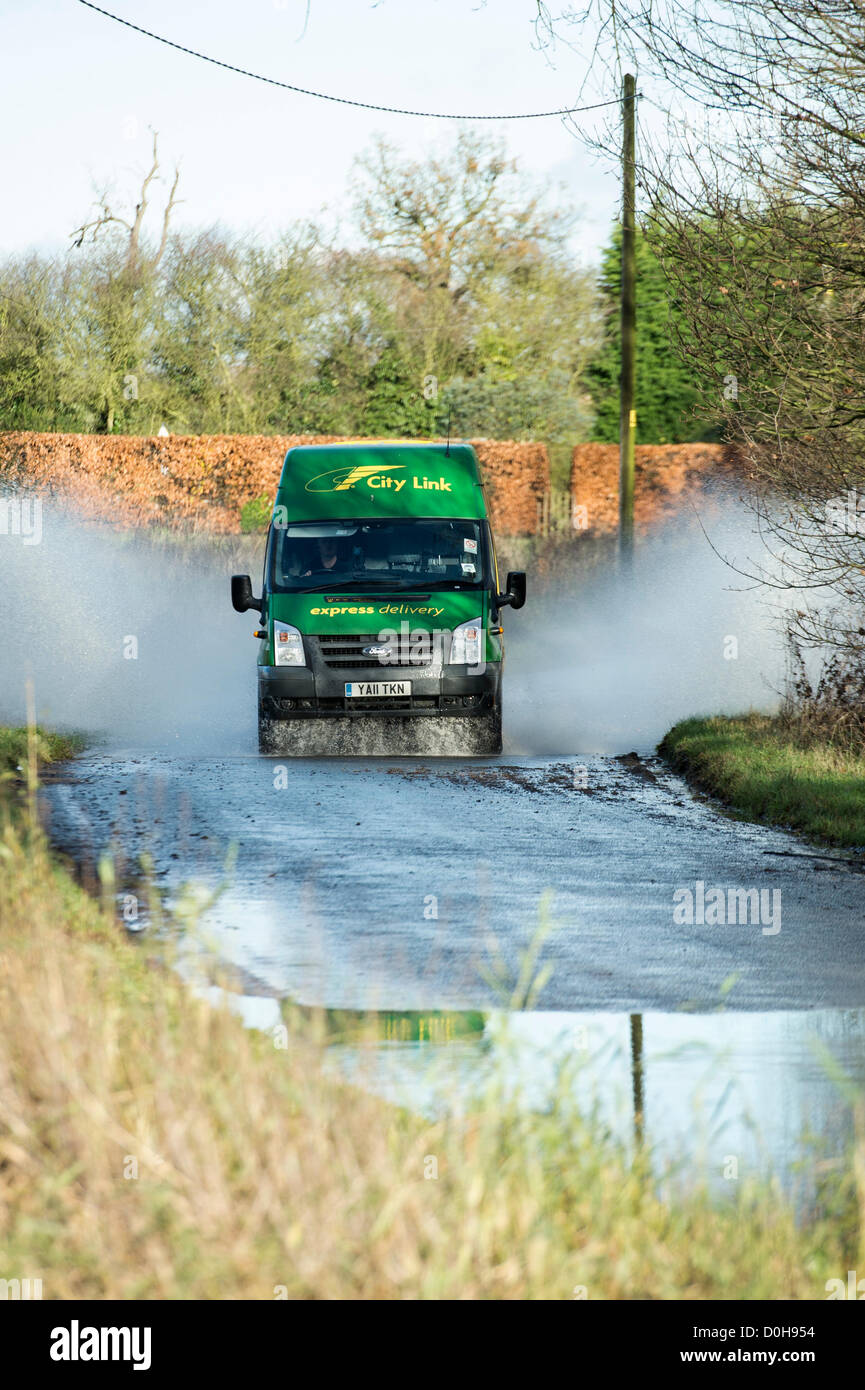 Billericay, Essex, Regno Unito. Ultimi heavy rain e saturo di acqua la massa ha portato ad un sacco di acqua di superficie in luoghi in Essex. Questo ha catturato alcuni piloti fuori in quanto colpiscono queste pozze a velocità che può condurre a motori allagata e arrivando a un arresto nell'acqua. Una città Link van fa scalpore attraverso l'acqua. Foto Stock