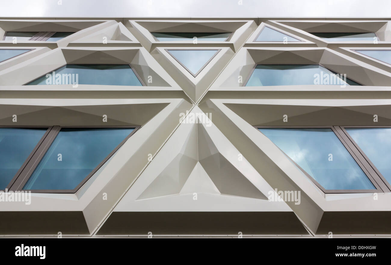 Moderna facciata di un edificio costituito da triangoli e windows in cui riflette il cielo Foto Stock
