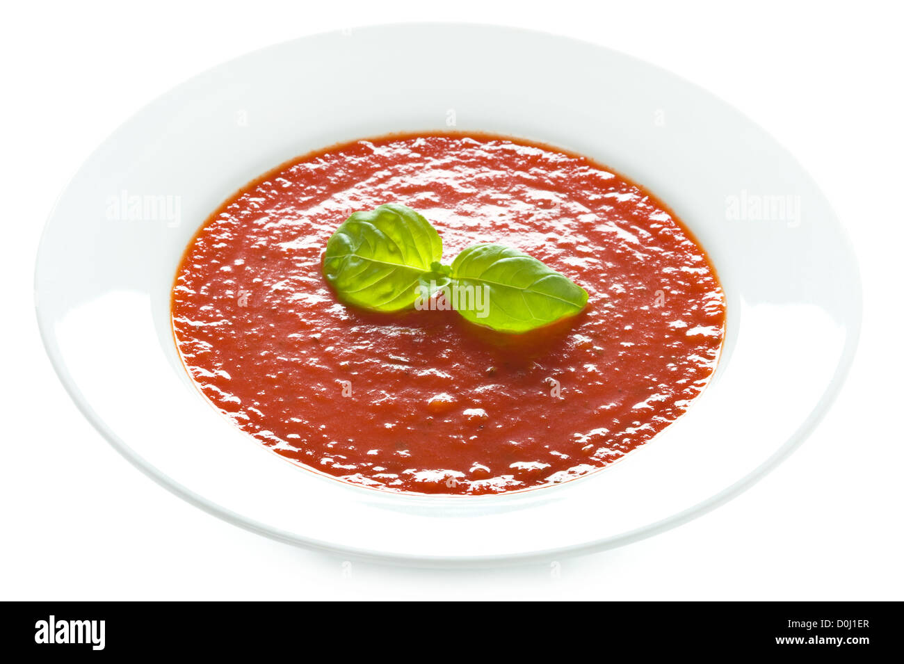 Zuppa di pomodoro con basilico guarnire in una ciotola bianco isolato Foto Stock