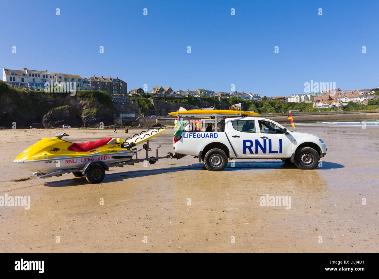 Bagnino RNLI veicolo e tavole da surf mantenendo vegli su Great Western Beach, Newquay, Cornwall Foto Stock