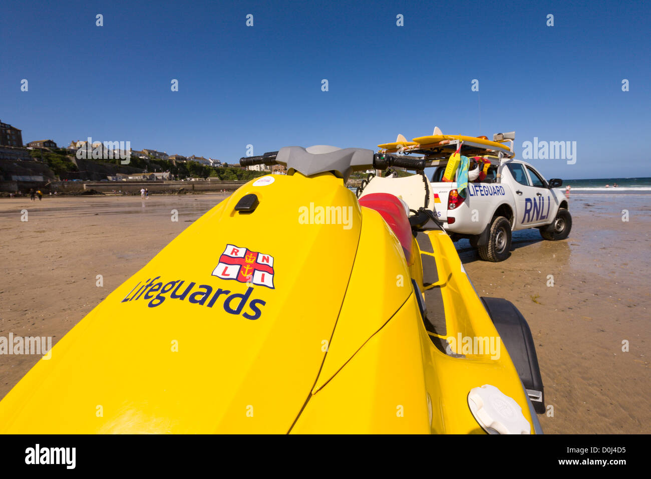 Bagnino RNLI veicolo e tavole da surf mantenendo vegli su Great Western Beach, Newquay, Cornwall Foto Stock