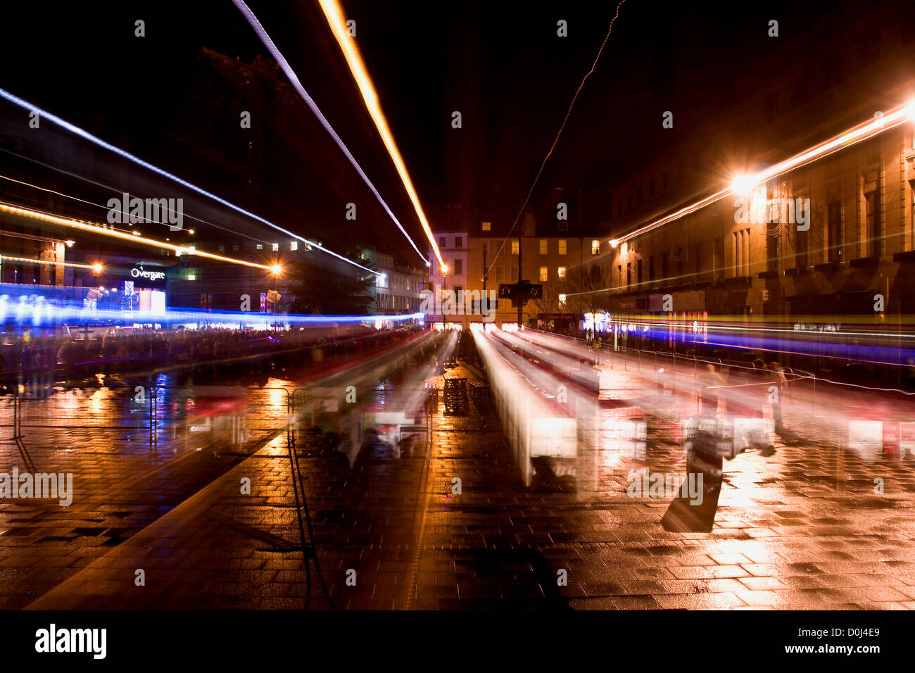 La folla e la strada dei riflessi di luce illuminando la città di notte sotto la pioggia mentre utilizzando la tecnica della telecamera a Dundee, Regno Unito Foto Stock