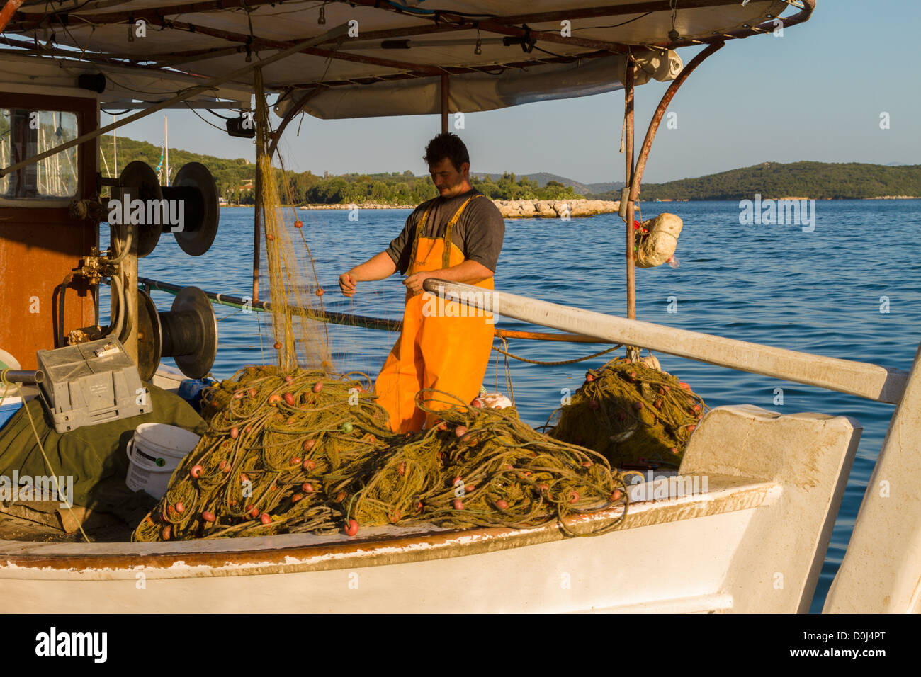 Pescatore sulla sua barca, controllare le sue reti, Vonitsa, Amvrakikos Kolpo, Grecia Foto Stock