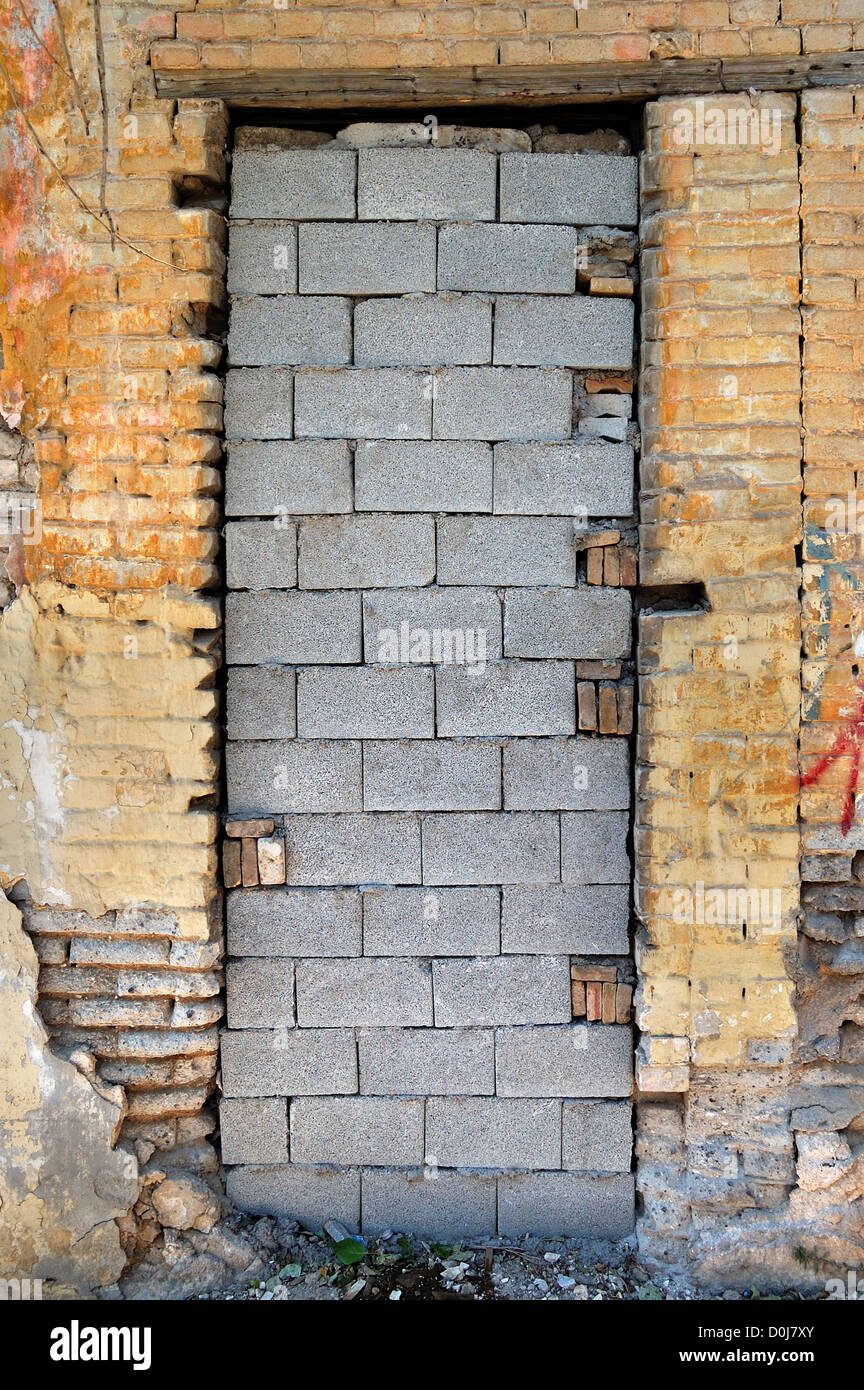 Murata porta e tagliò un muro di mattoni texture. Casa abbandonata esterno. Foto Stock