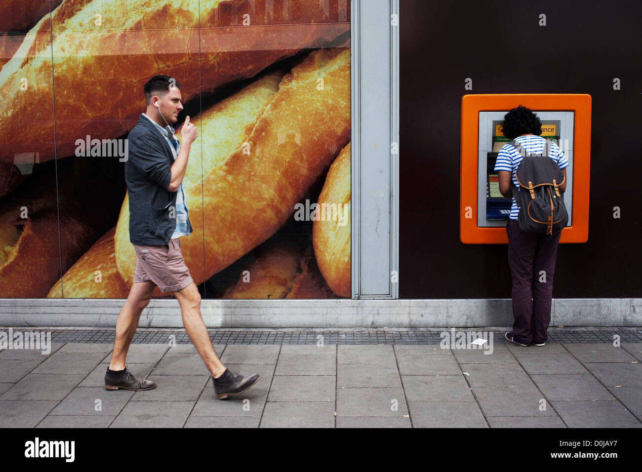 Un uomo camminare davanti a un bancomat a Broadmead in Bristol. Foto Stock