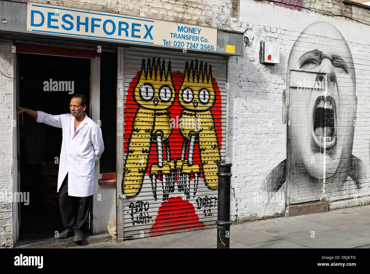 Un uomo che guarda verso la Brick Lane ingresso Hanbury Street con arte di strada. Foto Stock