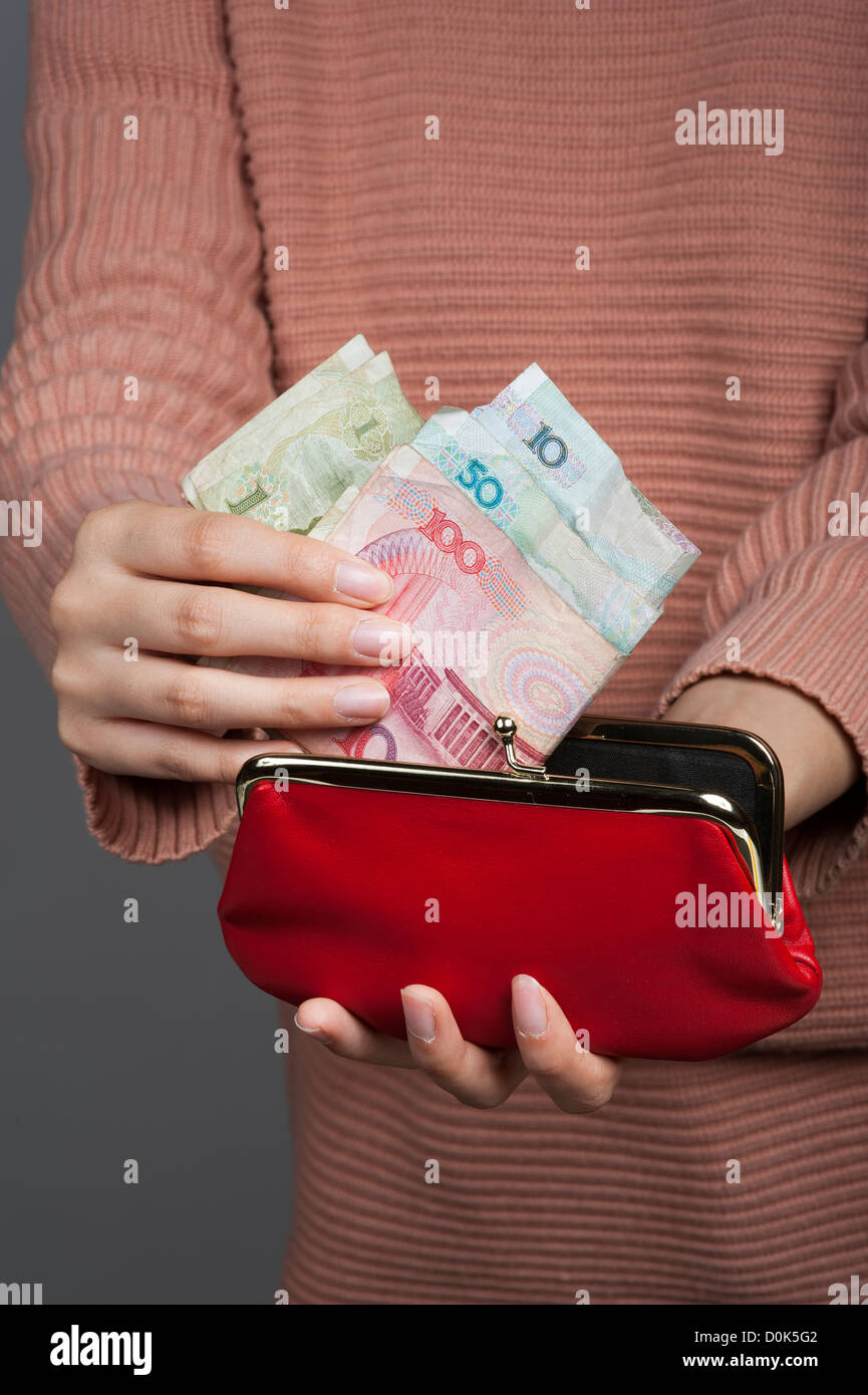 Donna cinese Yuan di contenimento di banconote la moneta ufficiale della Cina continentale con un portamonete rosso Foto Stock
