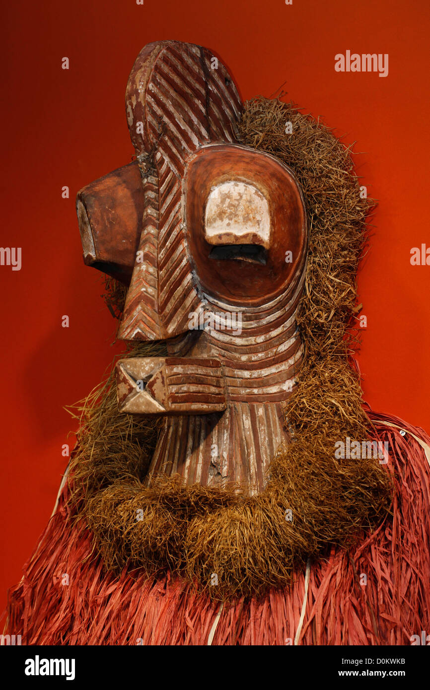 Una maschera africana, del popolo Yaka o Songye della Repubblica Democratica del Congo.in Africa caratterizzata dal suo viso allungato e intagliato in legno e da un grande copricapo in fibre vegetali, che sembra essere la rafia Foto Stock