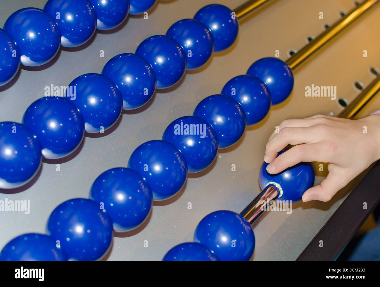 La mano muove le sfere blu sulla rotaia d'argento Foto Stock