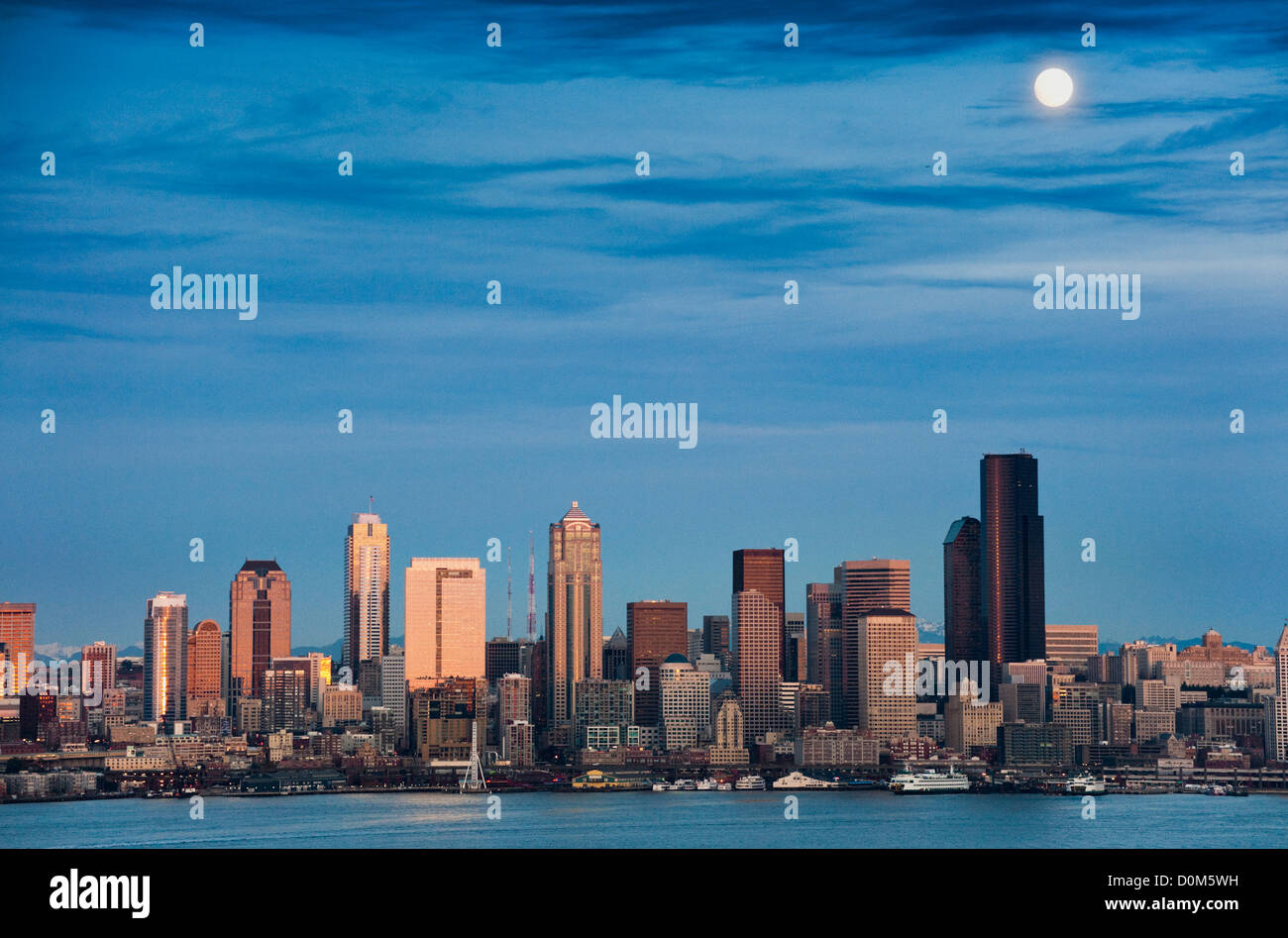 La luna piena sorge sopra la skyline di Seattle durante una chiara serata autunnale presi da Alki Beach in west Seattle. Foto Stock