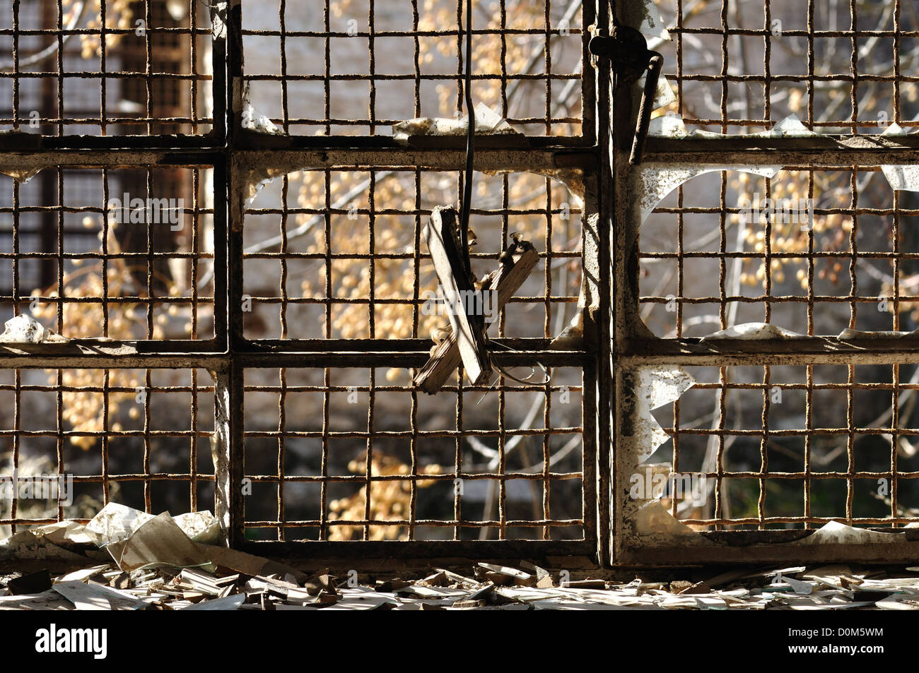 Rotto la finestra in vetro e rusty wire mesh background in magazzino abbandonato. Foto Stock