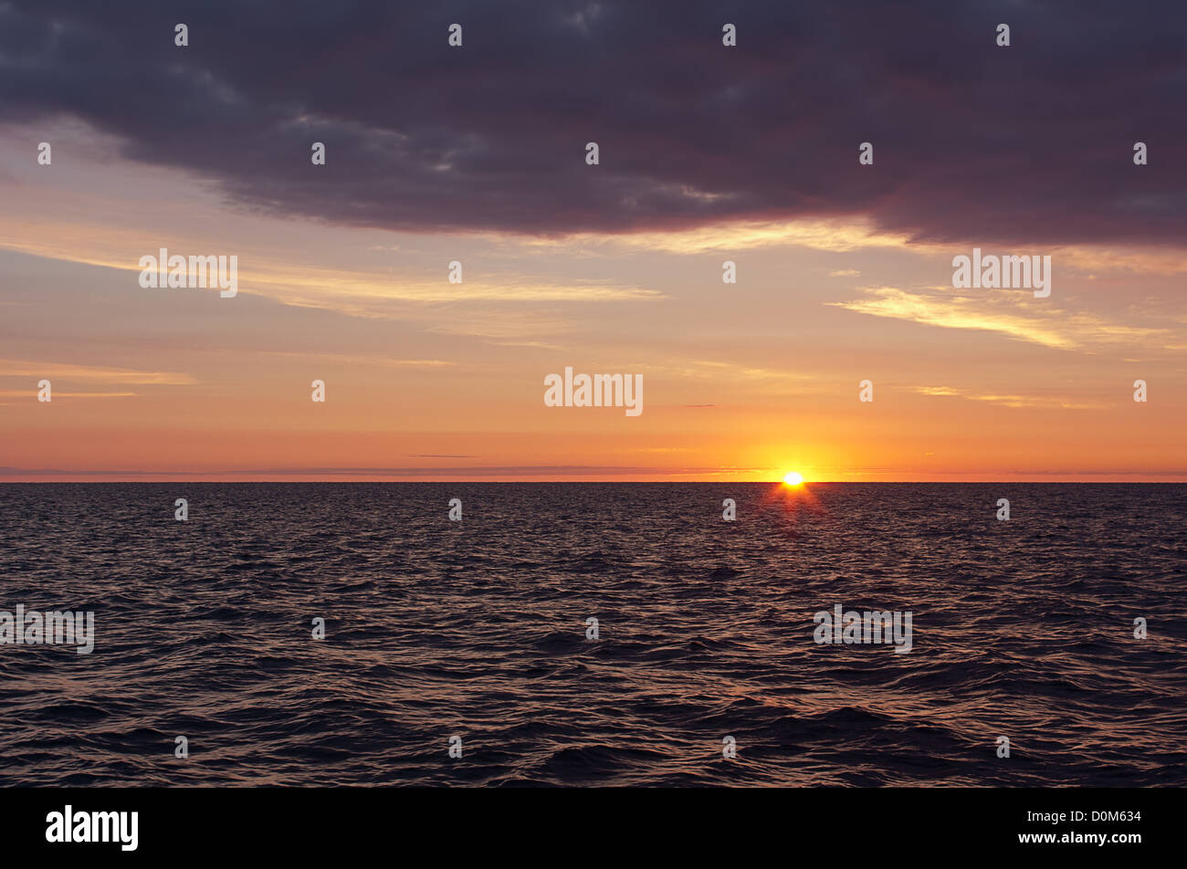 Un alba sopra l'acqua. Il sole è a metà strada sopra l'orizzonte. Foto Stock