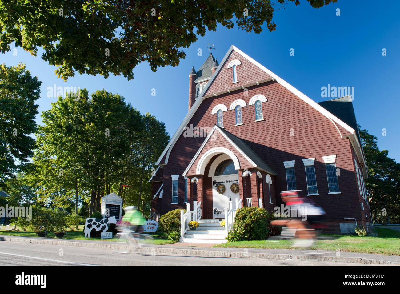 Silhouette sfocata di 2 ciclisti in sella passato Unione Chiesa congregazionale, York Beach, Maine, Stati Uniti d'America. Foto Stock
