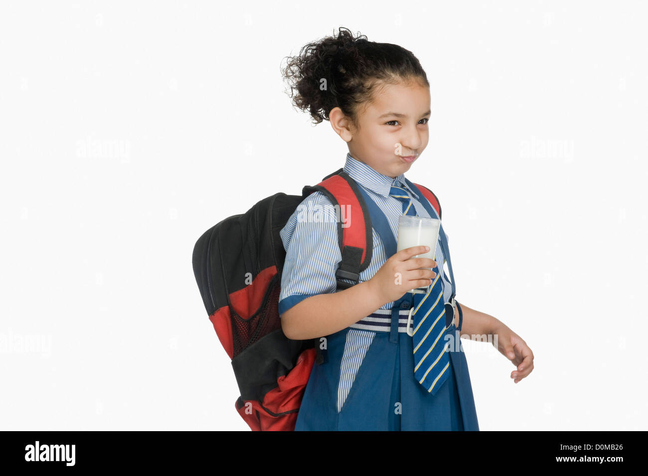 Schoolgirl tenendo un bicchiere di latte e facendo una faccia Foto Stock