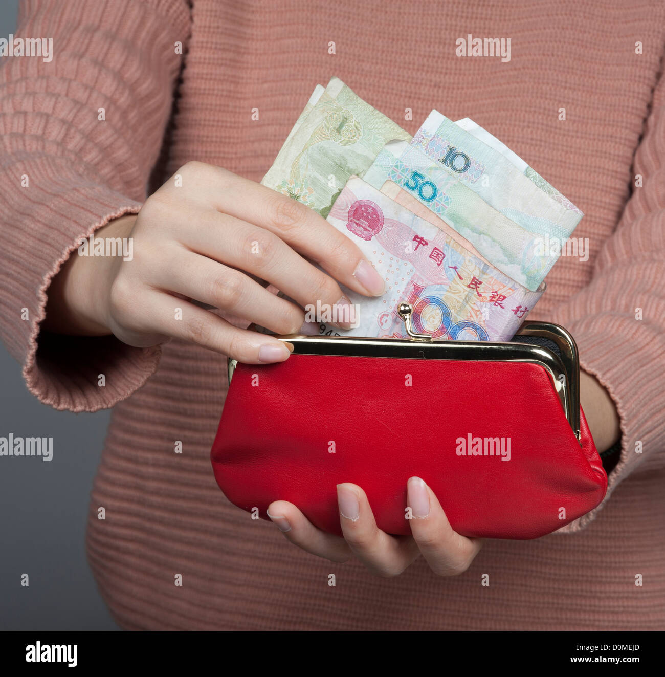 Donna cinese Yuan di contenimento di banconote la moneta ufficiale della Cina continentale con un portamonete rosso Foto Stock