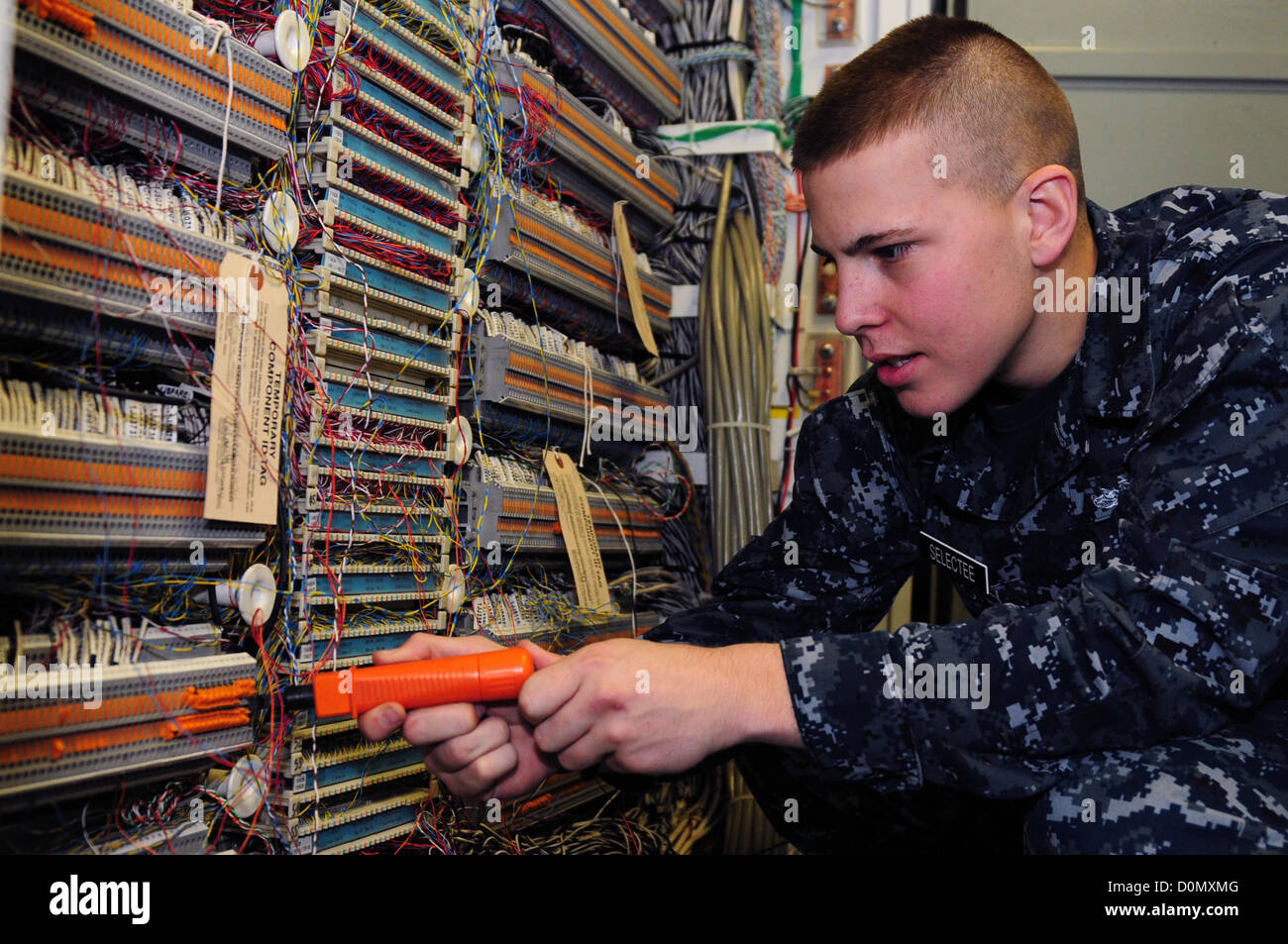 Il tecnico delle comunicazioni interne, il Fireman Michael Emory, lavora per installare linee telefoniche a bordo della USS Dwight D. Eisenhower (CVN 69), una portaerei classe Nimitz. La nave è schierata nella zona della 5th Fleet degli Stati Uniti per condurre operazioni di sicurezza marittima. Foto Stock