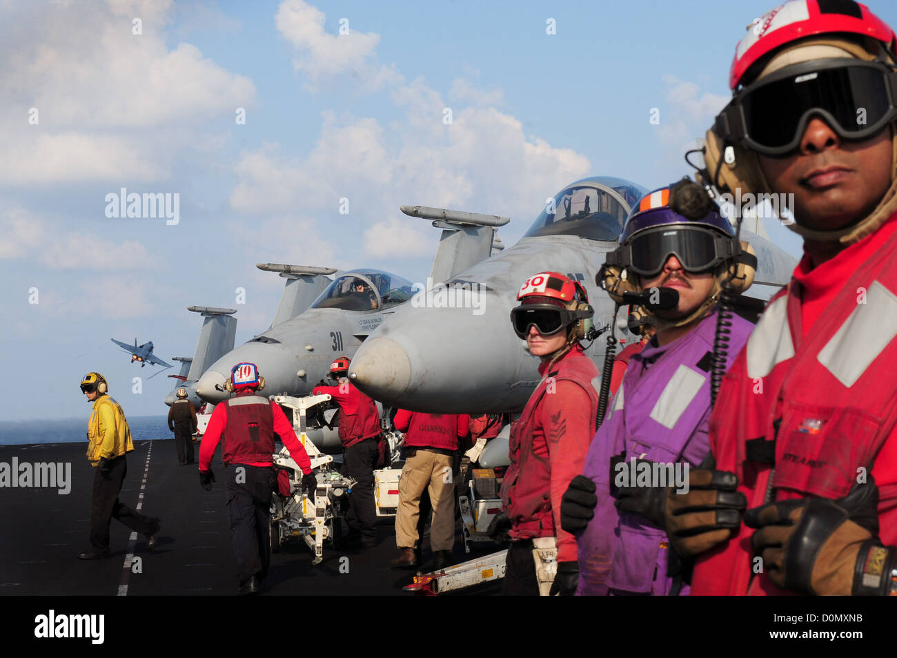 I marinai osservano come un F/A-18 Hornet si lancia dalla cabina di pilotaggio della USS Dwight D. Eisenhower (CVN 69) mentre è schierato nella 5th Fleet, conducendo operazioni di sicurezza marittima e di sicurezza teatrale. Foto Stock
