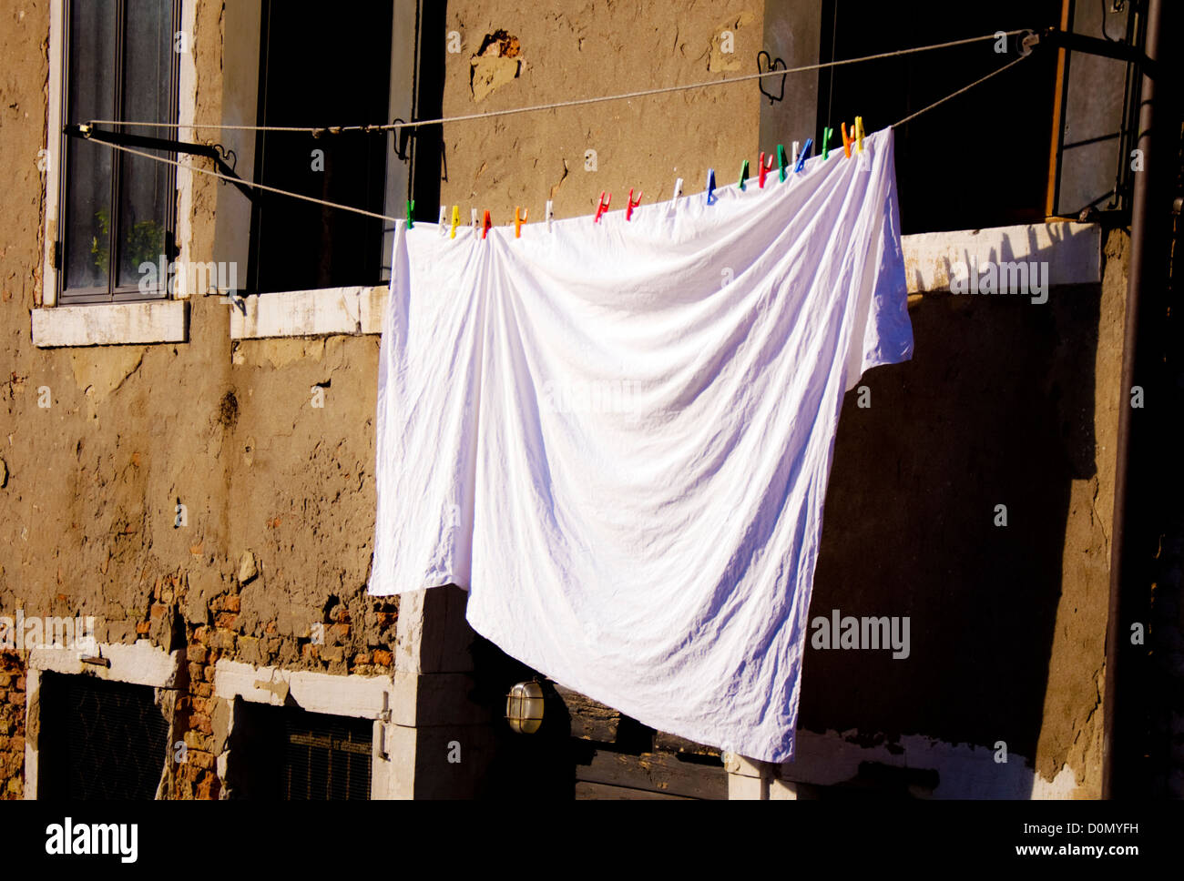 Foglio bianco appeso sulla linea con molti in plastica colorata pioli di vestiti Foto Stock