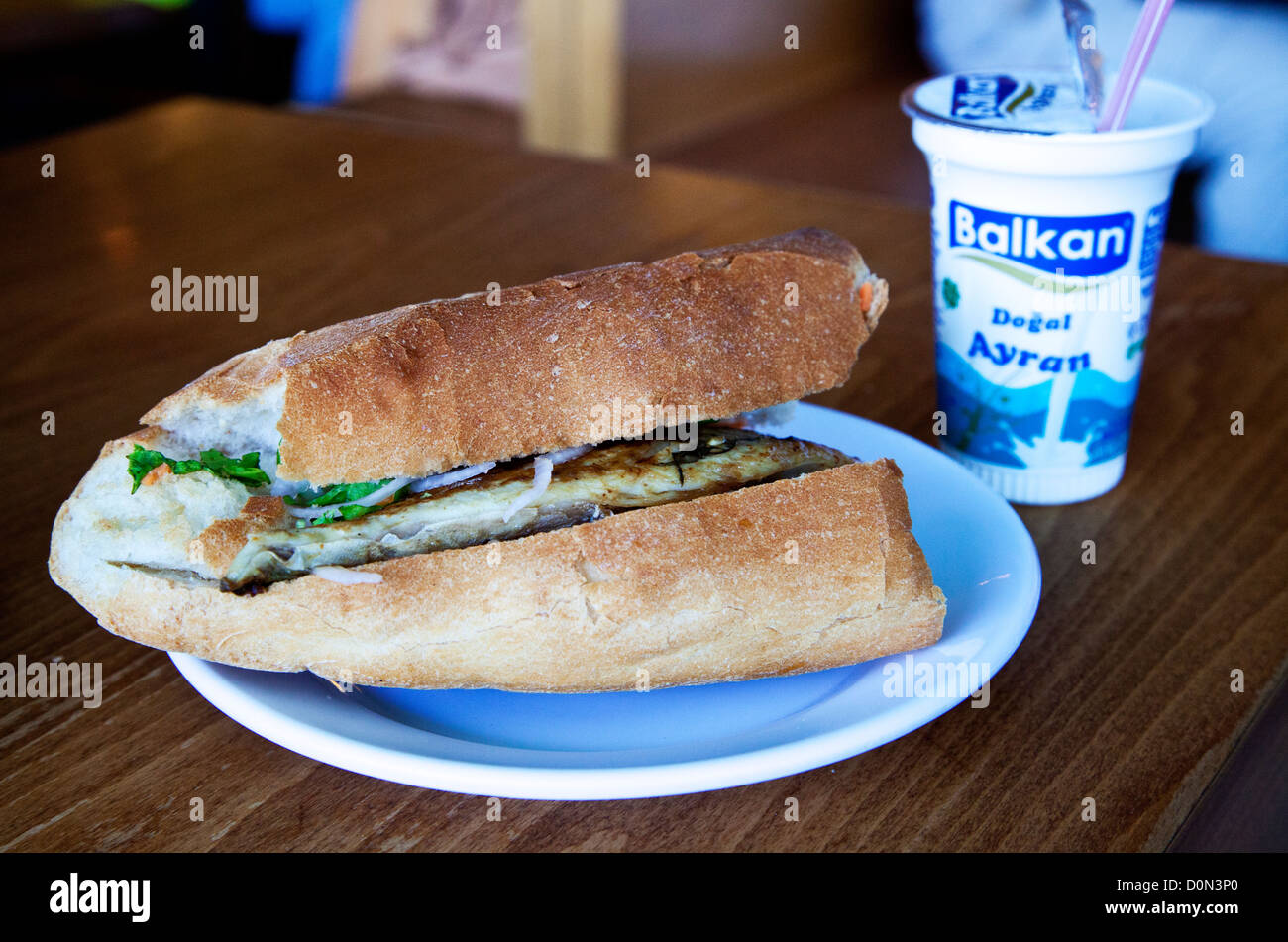 Balik ekmek (pesce sandwich) mangiato sotto il ponte a Eminonu, Istanbul. Servita con la bevanda tradizionale, ayran. Foto Stock
