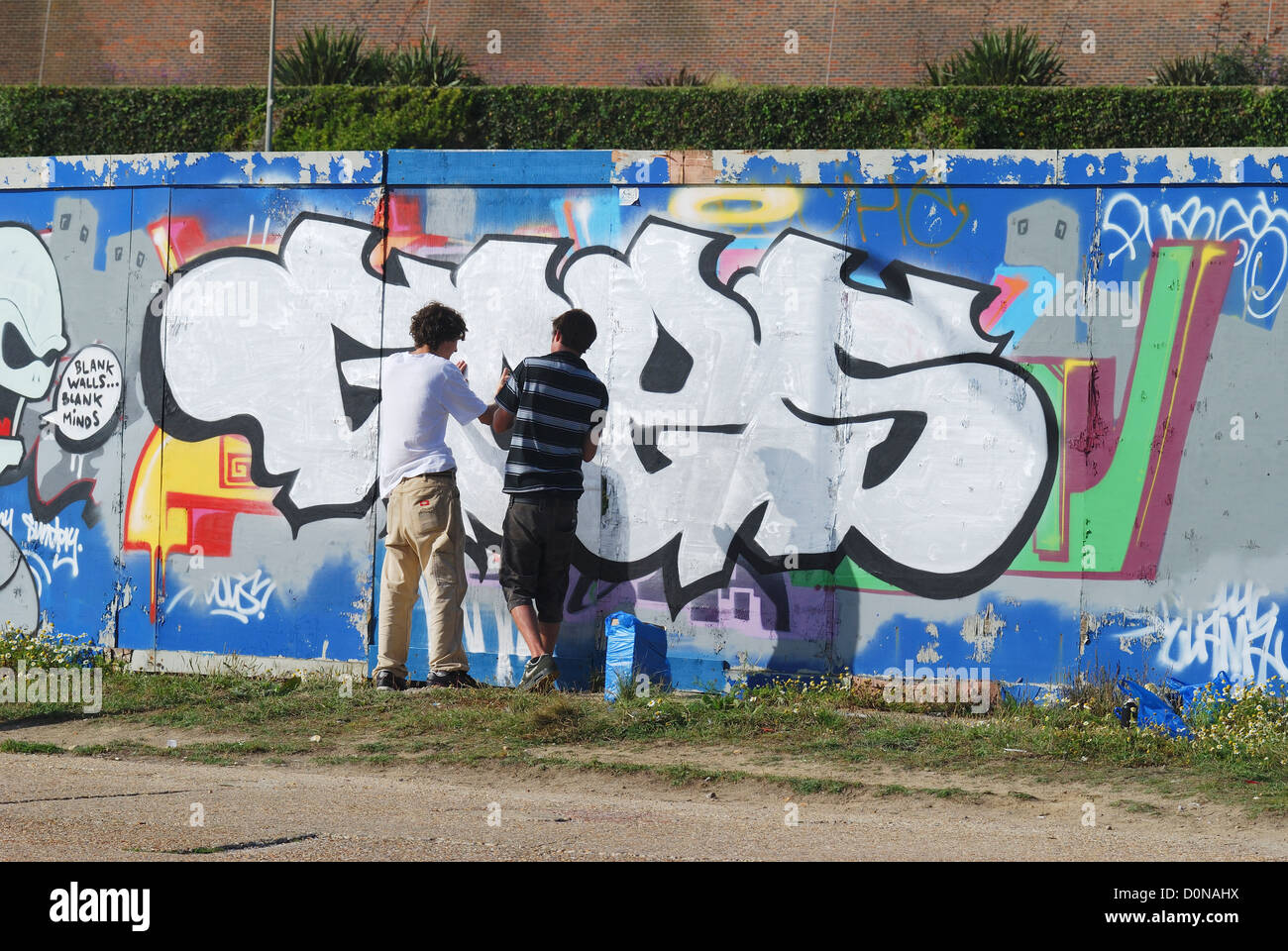 Ragazzi dipinto graffiti sul muro utilizzando le bombolette ad aerosol. Brighton Seafront. East Sussex. In Inghilterra. 14/8 Foto Stock