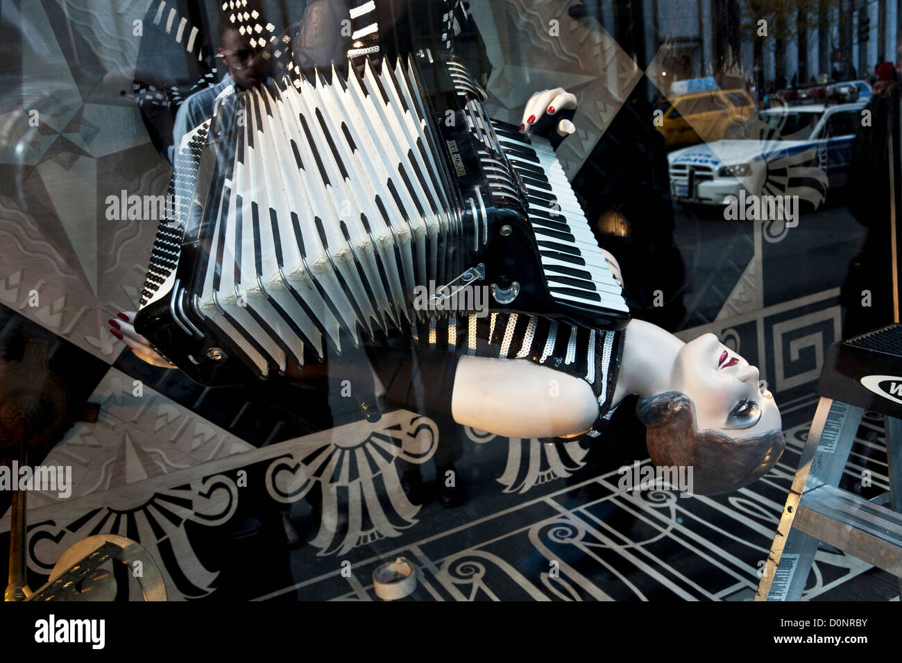 Mannequin reclinabili con scarlatto labbra chiodi suona fisarmonica vintage in Bergdorf Goodman Follie 2012 a tema nella finestra di Natale Foto Stock