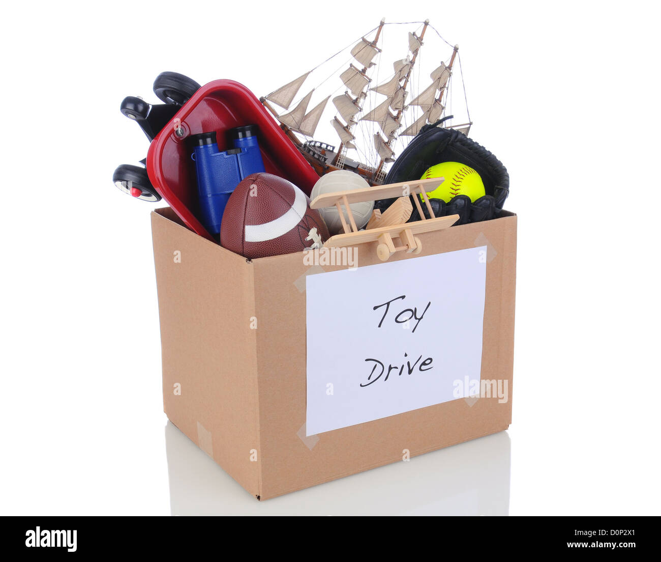 Una scatola piena di giocattoli e attrezzature sportive per una vacanza carità drive. Isolato su bianco con la riflessione. Foto Stock