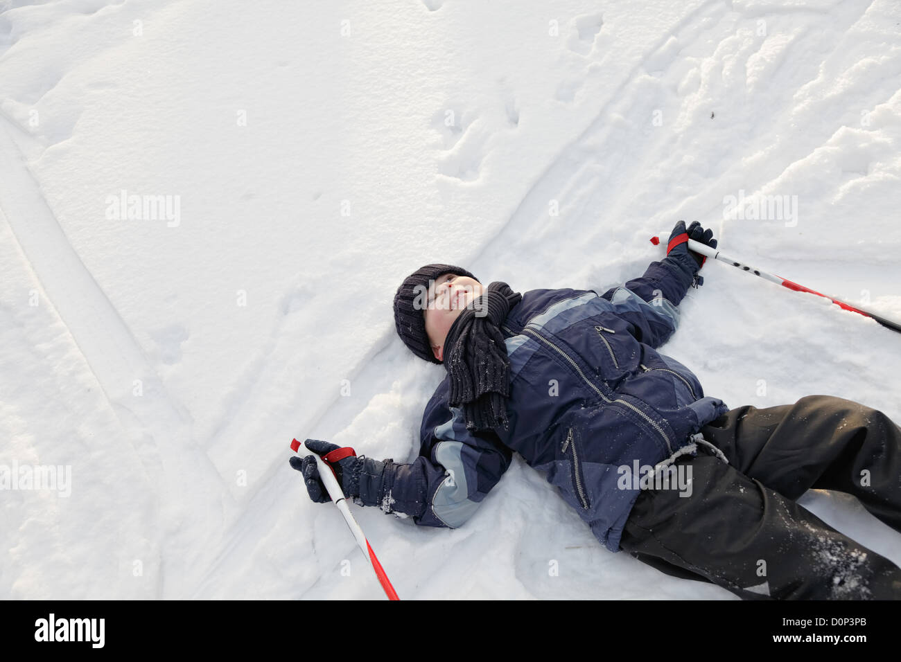 Ragazzo sorridente che stabilisce sulla neve Foto Stock