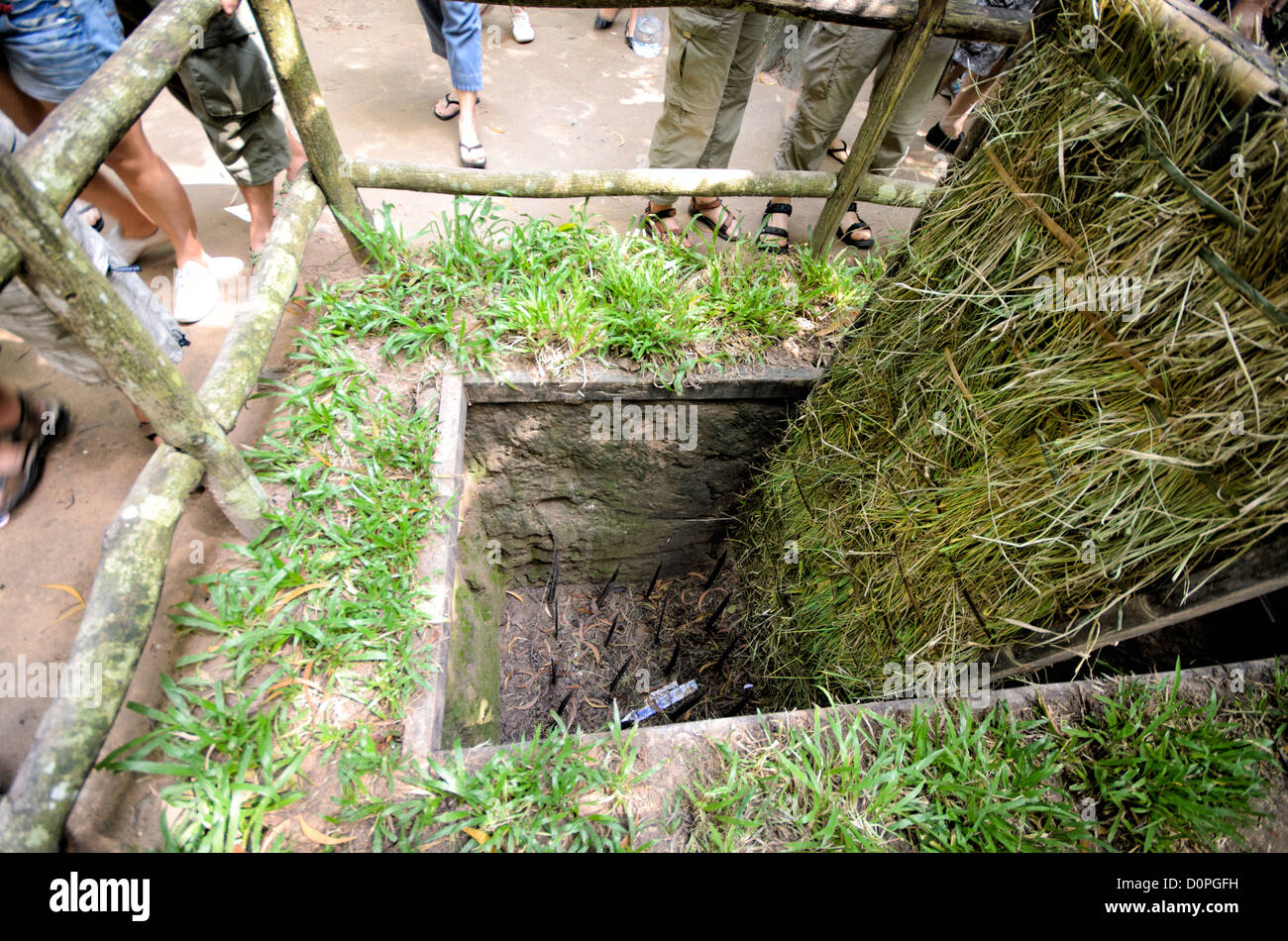 Tunnel di Cu chi Punji Trap ho chi Minh City Vietnam // CITTÀ DI HO CHI MINH, Vietnam - Una guida turistica mostra una trappola punji conservata presso il sito storico di Cu chi Tunnels, mostrando ai visitatori una delle misure difensive utilizzate durante la guerra del Vietnam. La trappola mimetica presenta una fossa nascosta con punte metalliche, che rappresenta il tipo di tecnica difensiva comunemente utilizzata durante tutto il conflitto. I tunnel di Cu chi, situati a nord-ovest della città di ho chi Minh, servivano come un'estesa rete sotterranea utilizzata dalle forze vietnamite. La dimostrazione fa parte delle mostre educative del sito che si occupano di Foto Stock