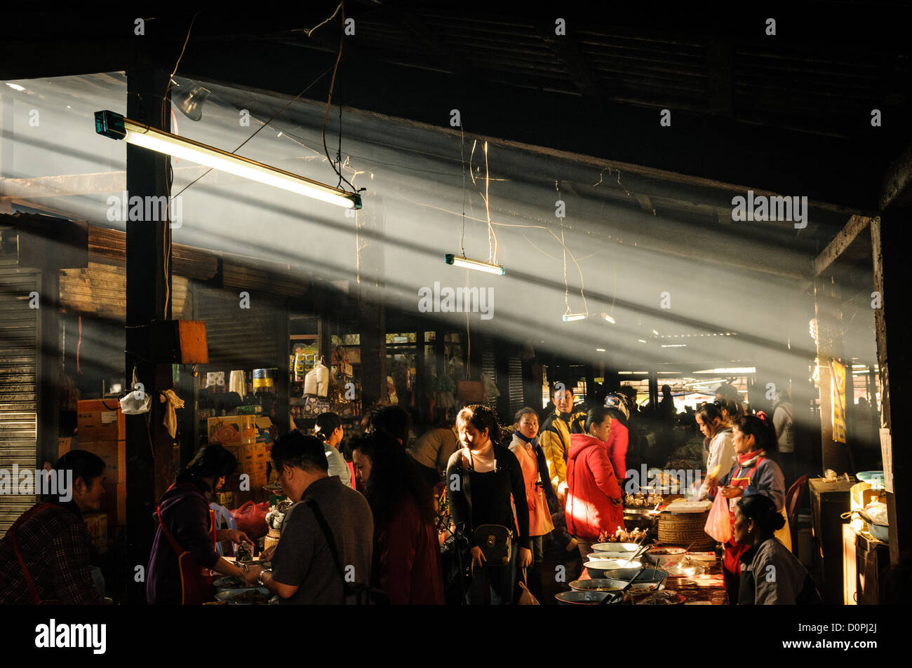 PHONSAVAN, Laos — PHONSAVAN, Laos - la luce del sole del mattino cattura il fumo mentre i venditori al mercato mattutino di Phonsavan nel nord-est del Laos vendono un'ampia gamma di cibi freschi e cucina locale, tra cui passero alla griglia, maiale, pollo, insetti, ratti di bambù, e cane. La popolazione della regione è prevalentemente di etnia Hmong. Foto Stock