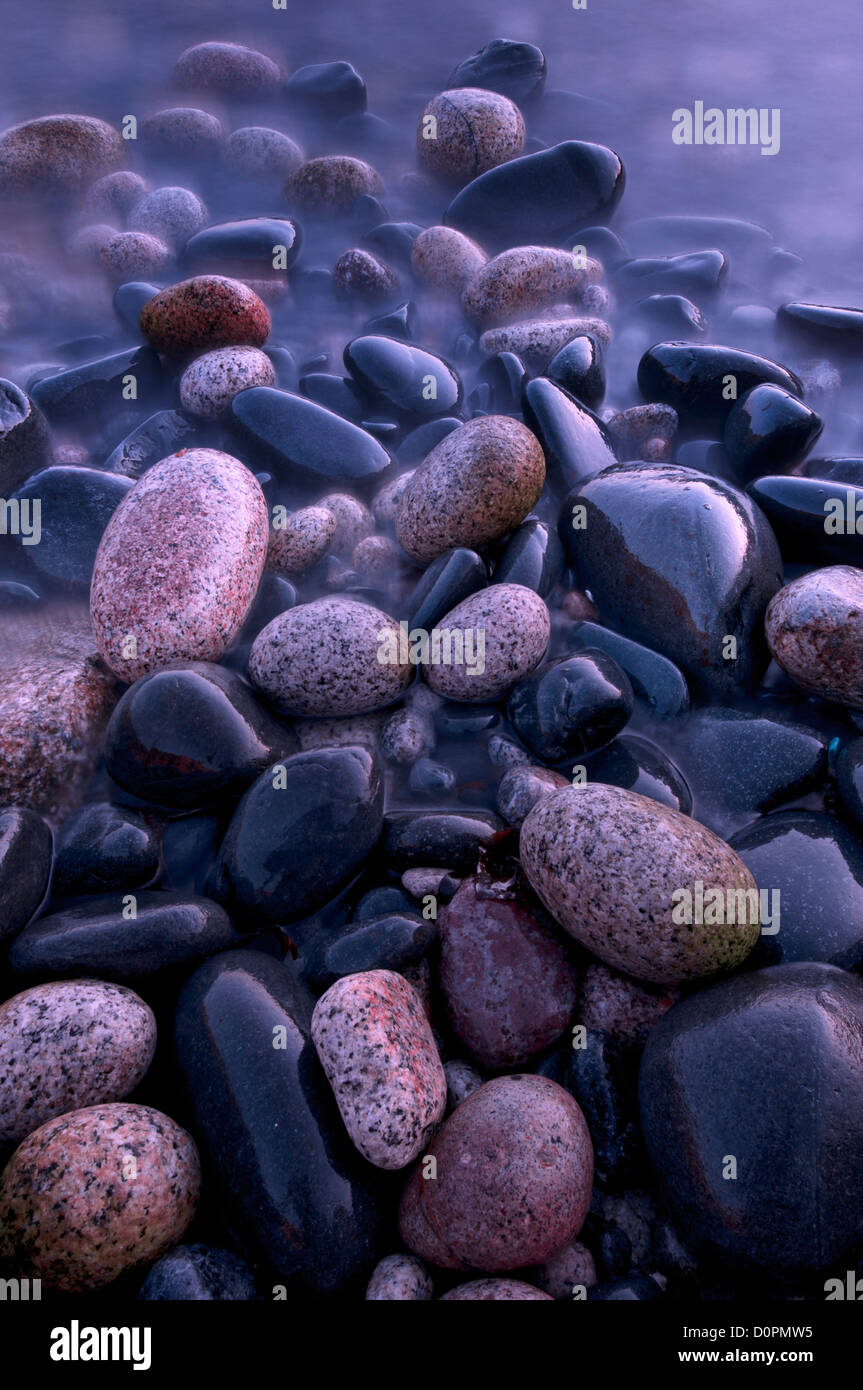 Wet, mare pietre levigate sulla riva della spiaggia Nanven, Cot Valley, Cornwall Foto Stock