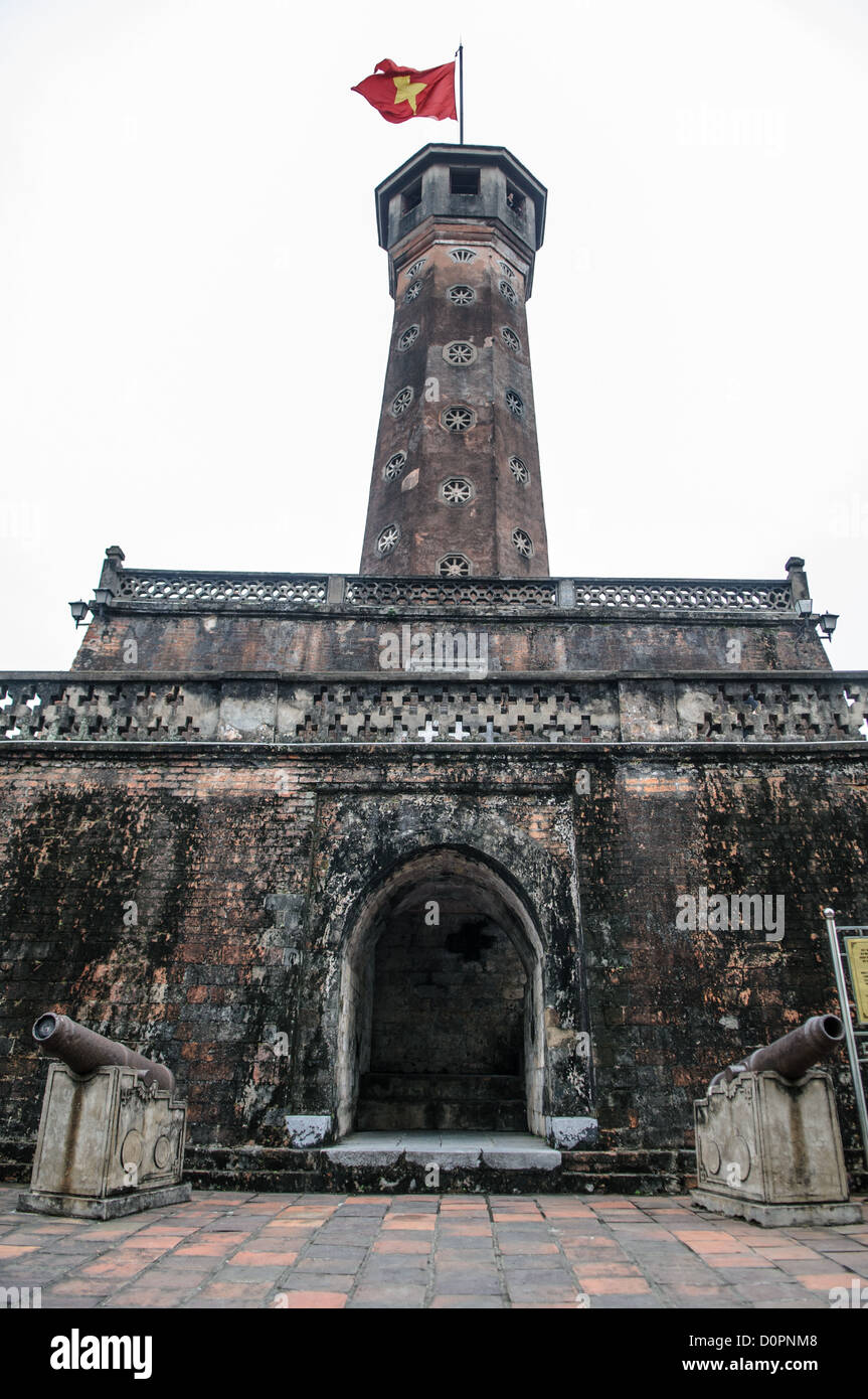 Torre della bandiera di Hanoi Museo di storia militare del Vietnam Hanoi Vietnam // HANOI, Vietnam - la storica Torre della bandiera di Hanoi, costruita tra il 1805 e il 1812, si erge a 33,5 metri di altezza presso il Museo di storia militare del Vietnam. La torre presenta una scala a chiocciola di 54 gradini che conduce ad una sala di osservazione e ha sventolato la bandiera nazionale vietnamita ininterrottamente dal 10 ottobre 1954. Questa reliquia storica e culturale nazionale è sia un simbolo dell'indipendenza vietnamita sia un punto di riferimento centrale del complesso museale militare. La struttura ottagonale rappresenta uno dei pochi elementi architettonici rimasti da Foto Stock