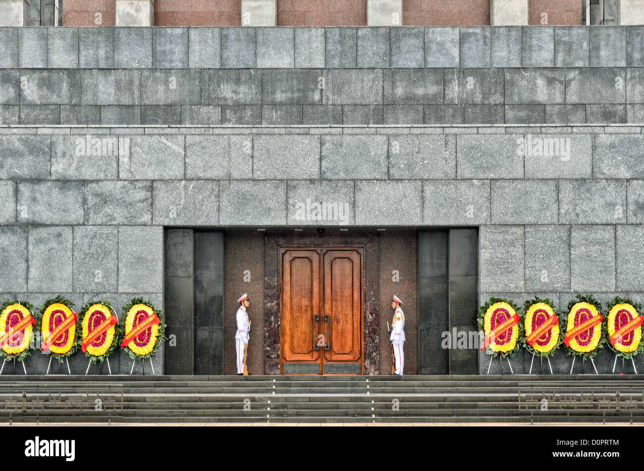 HANOI, Vietnam - due soldati in uniformi di cerimoniale guardia di fronte al mausoleo di Ho Chi Minh, sopraffatte da blocchi di granito dell'edificio. Un memoriale di grandi dimensioni nel centro di Hanoi circondato da Ba Dinh Square, il Mausoleo di Ho Chi Minh ospita il corpo imbalsamato dell ex leader vietnamita e presidente fondatore Ho Chi Minh. Foto Stock