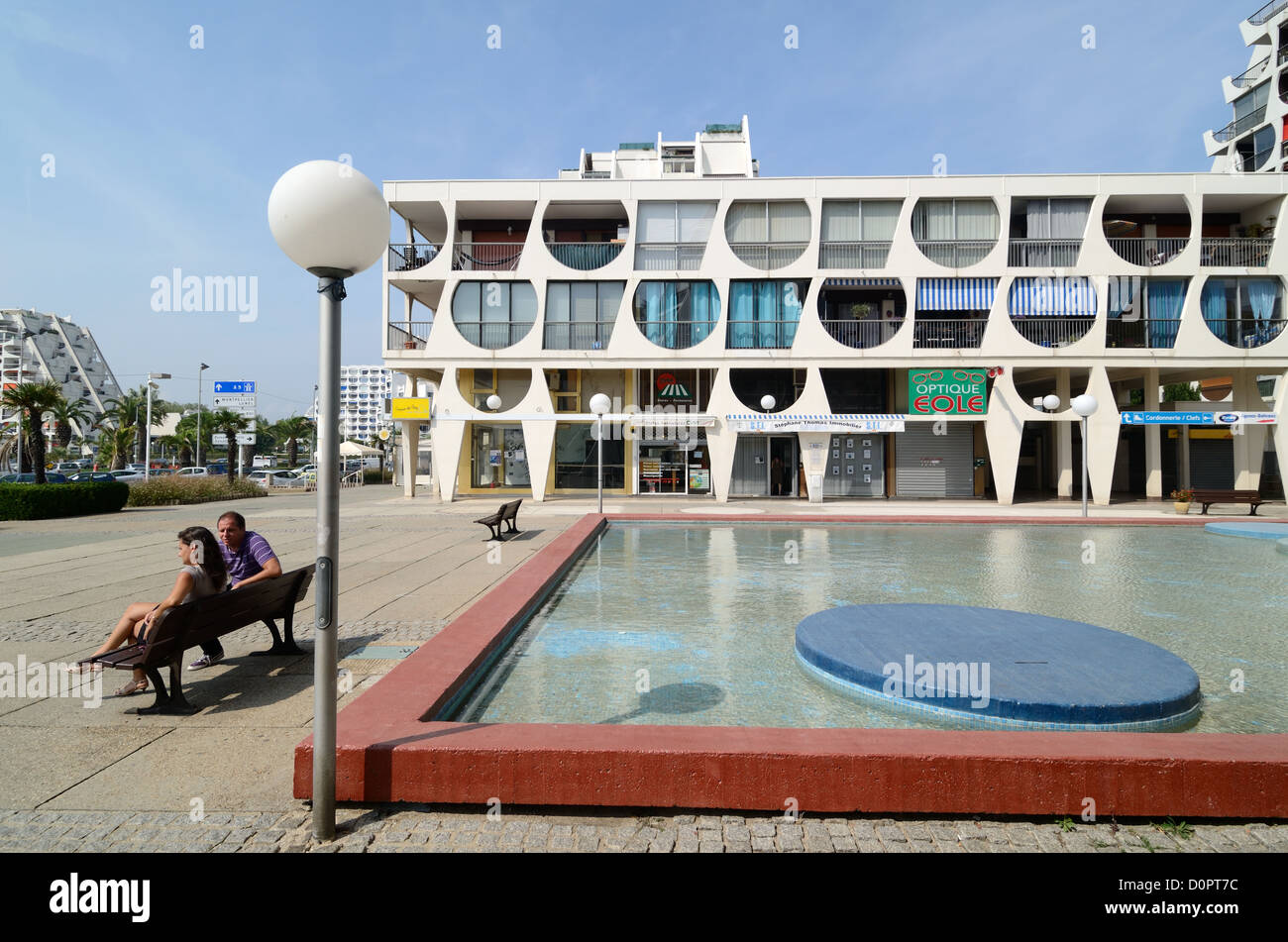 Turisti di fronte al Delta Building (1971) da Jean Balladur Town Square e Ornamental Pool a la Grande-Motte Resort Town Hérault France Foto Stock