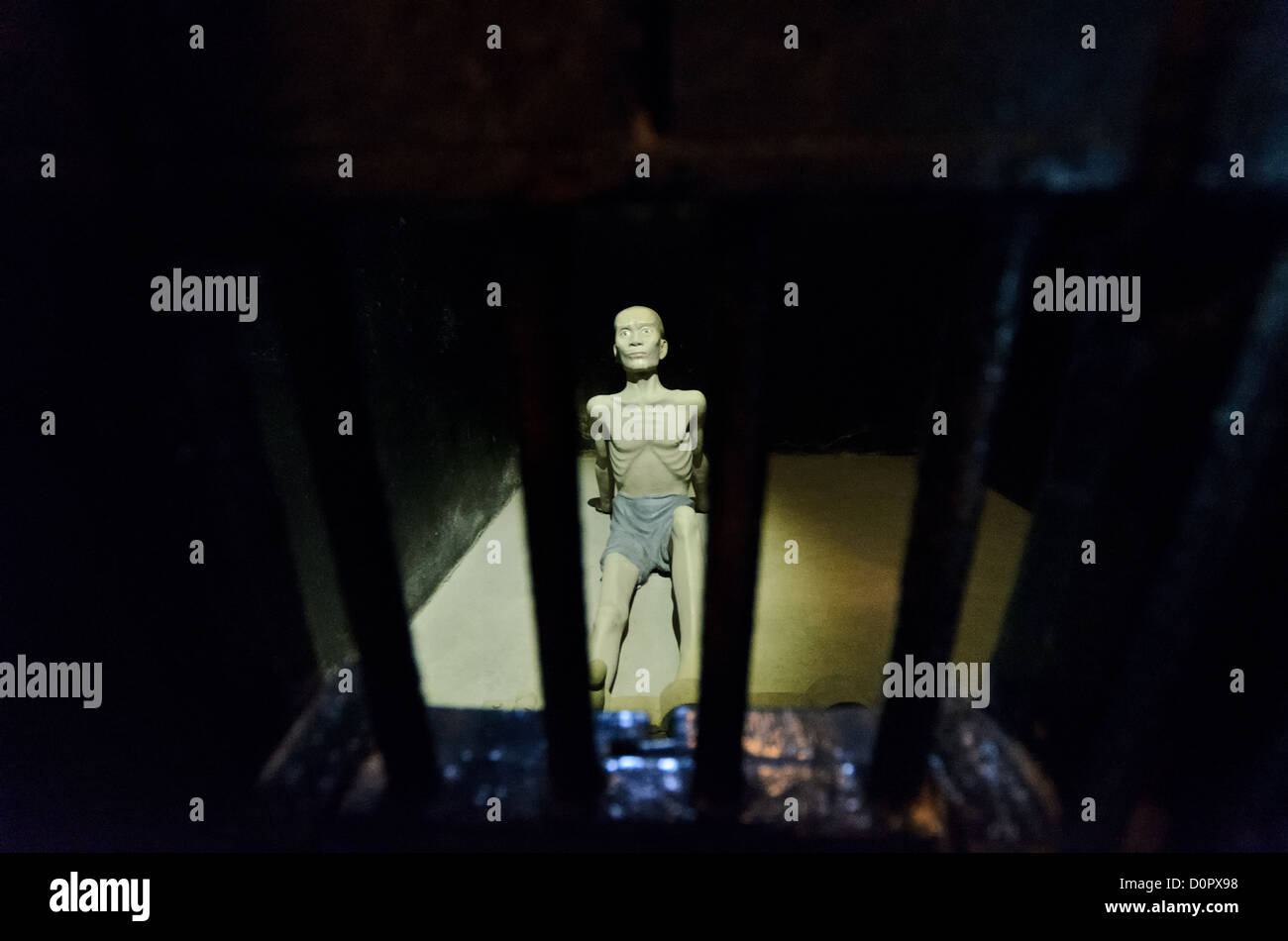 Cella di isolamento della prigione di Hoa lo Hanoi Vietnam // HANOI, Vietnam — Una figura scolpita viene utilizzata per dimostrare le condizioni nelle celle di isolamento nel sotterraneo della prigione di Hoa lo. Le barre in primo piano sono nella piccolissima finestra della porta. La prigione di Hoa lo, nota sarcasticamente come Hanoi Hilton durante la guerra del Vietnam, era originariamente una prigione coloniale francese per prigionieri politici e poi una prigione nordvietnamita per prigionieri di guerra. È particolarmente famosa per essere la prigione utilizzata per i piloti americani abbattuti durante la guerra del Vietnam. Foto Stock